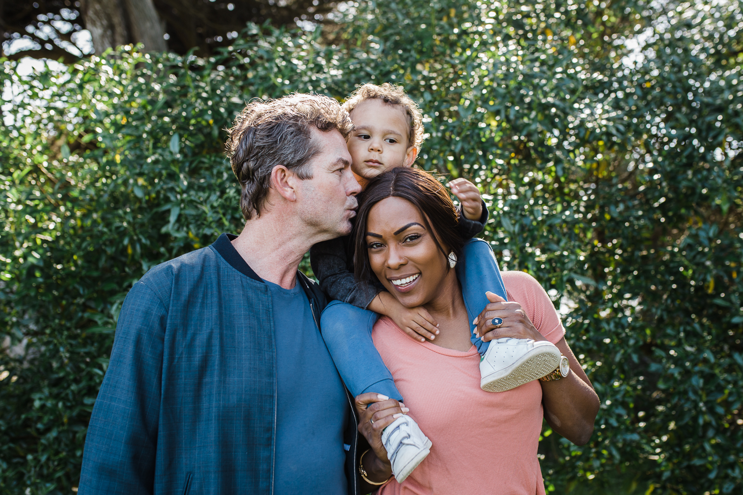 Family portrait with Dad kissing mom and mom looking at the camera {San Francisco Family Photographer}