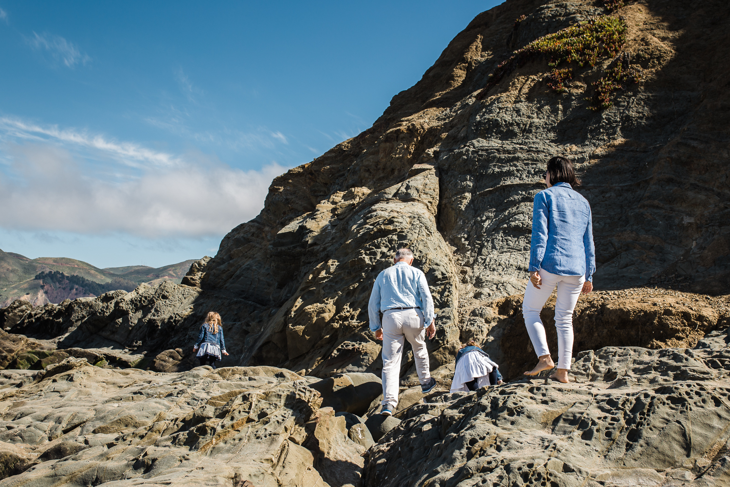 Family of four climbing on the rocks together at Baker Beach {San Francisco Lifestyle Photographer}