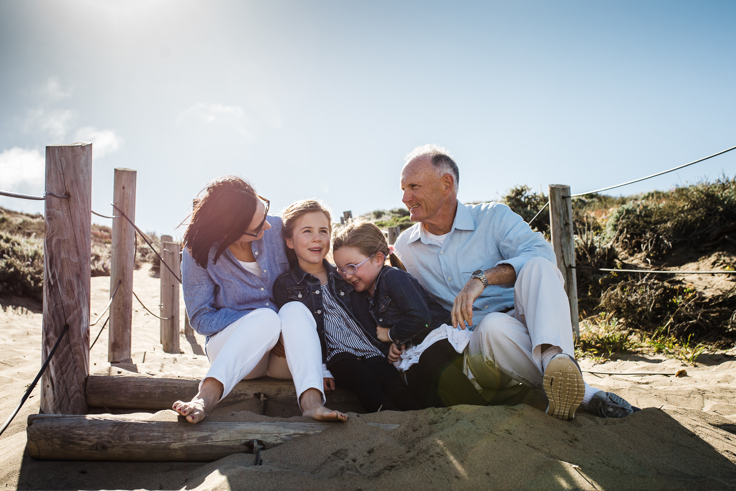 family portrait of twin five year old girls and mom and dad at Bakerbeach - sitting on sand stairs and looking at each other {San Francisco Family photographer}