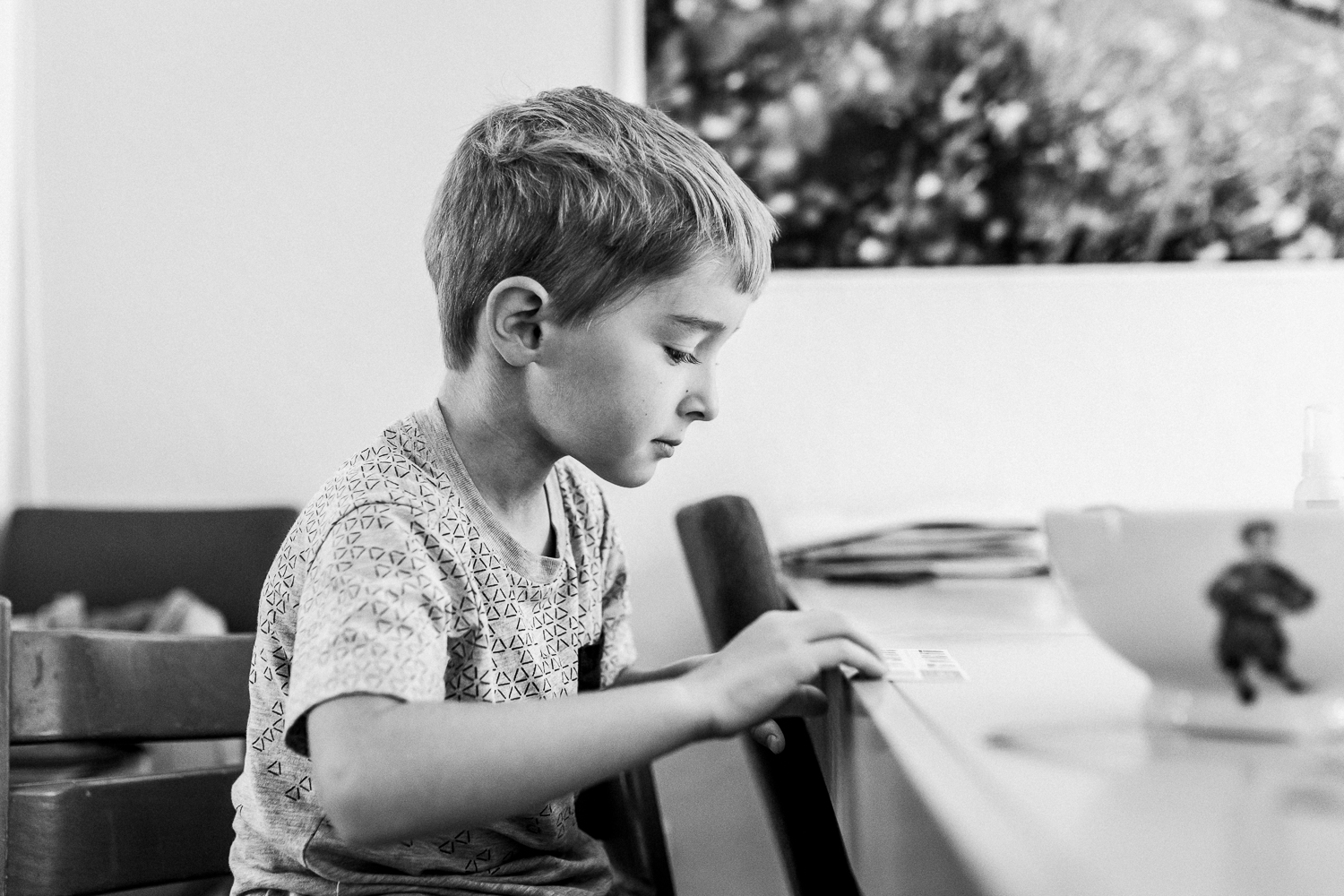 five year old boy sitting at the kitchen table looking at a paper