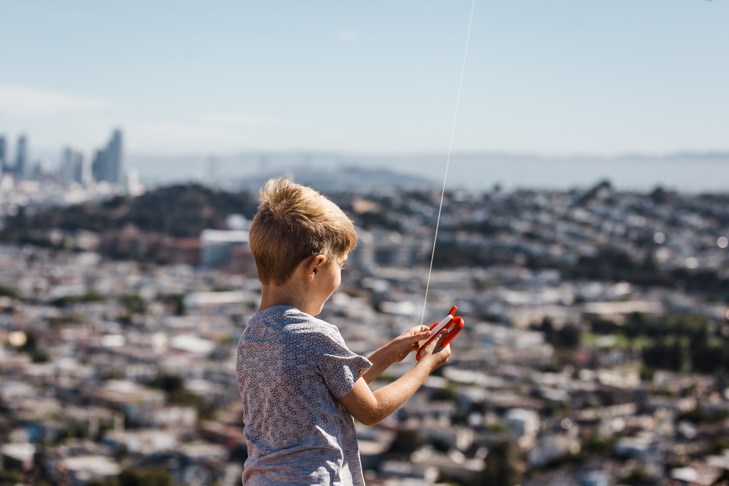 five year old little boy holding his kite with a view San Francisco in the background from Bernal Hill