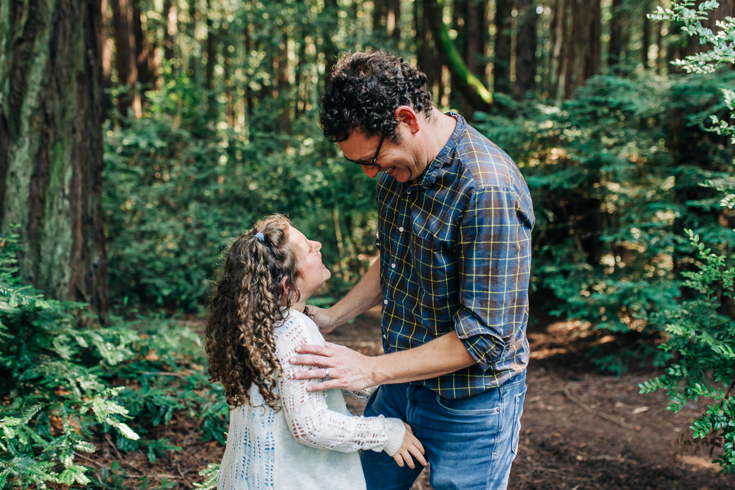 father and daughter looking at each other and smiling while playing in the woods {Oakland Family Photographer}