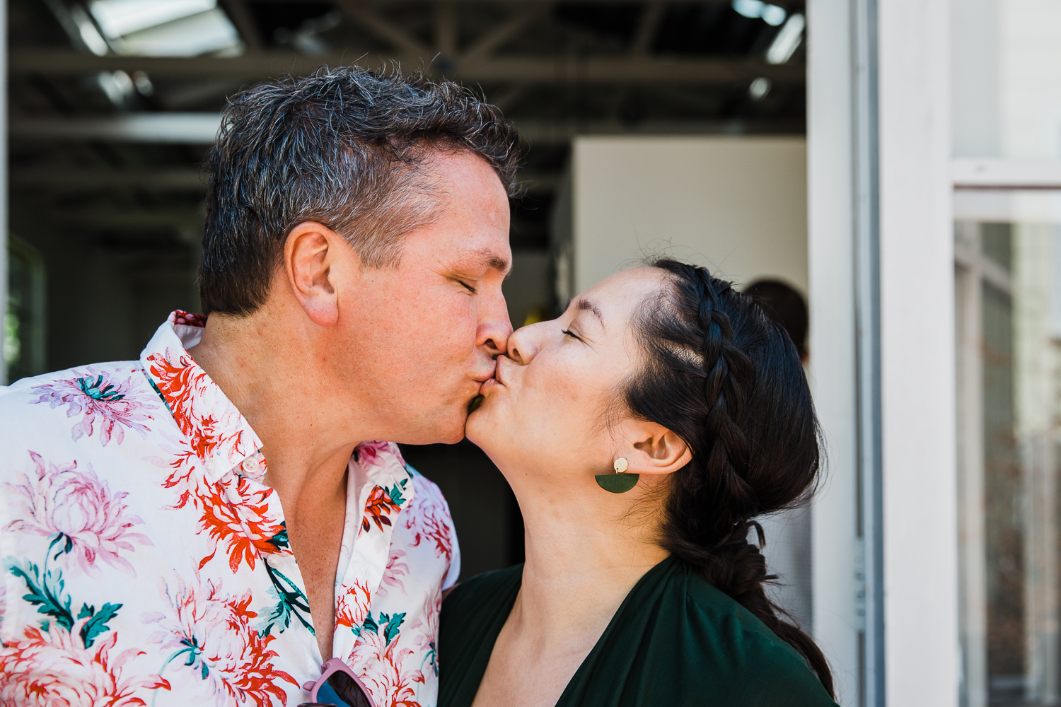 man and woman kissing each other with eyes closed outdoors