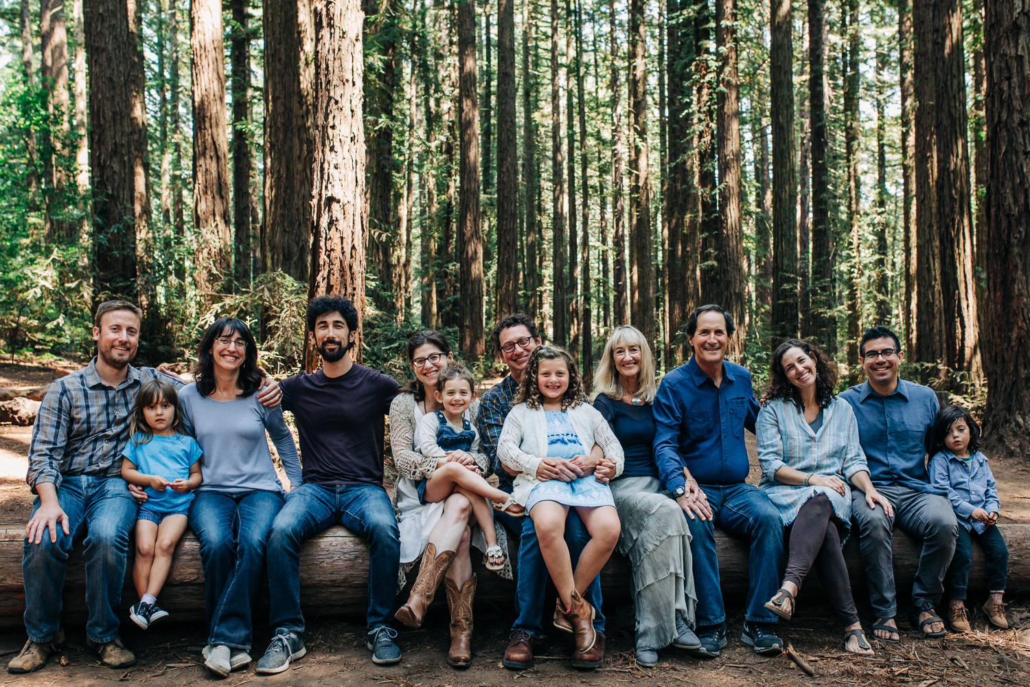 Extended family portrait shot of everyone sitting on a log bench and looking at the camera {Oakland Lifestyle Photographer}