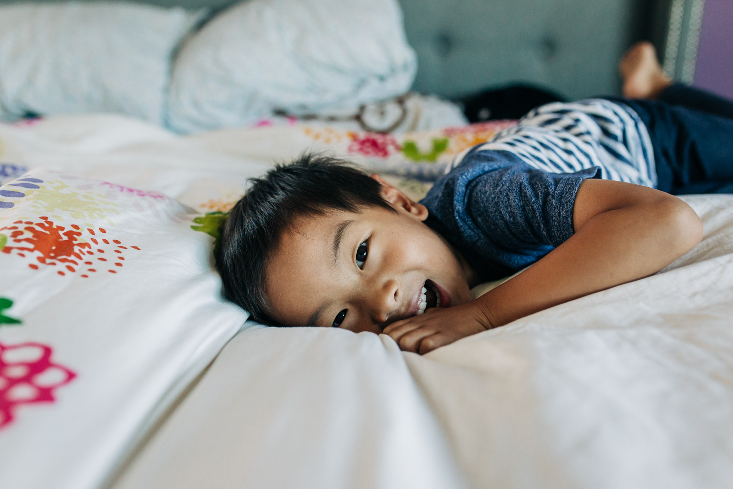 boy laying on a bed and looking and smiling at the camera 