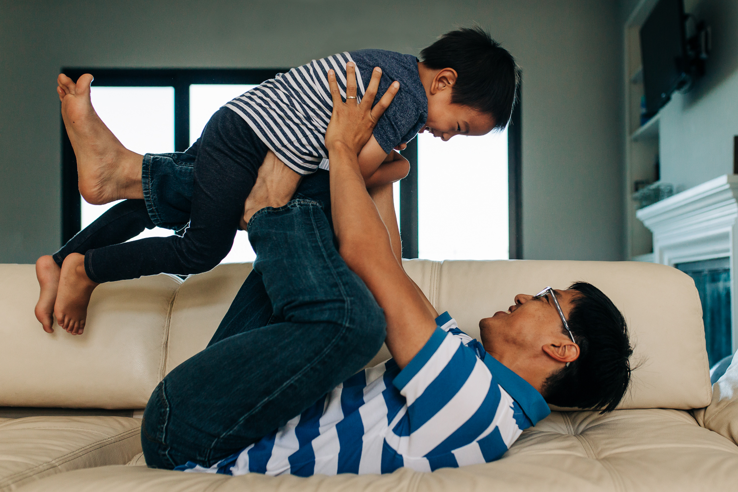 a dad holding of his little boy on his legs while they play and wrestle 