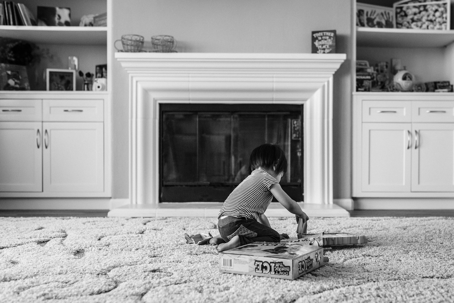 little girl sitting in front of a fireplace setting up a board game to play 