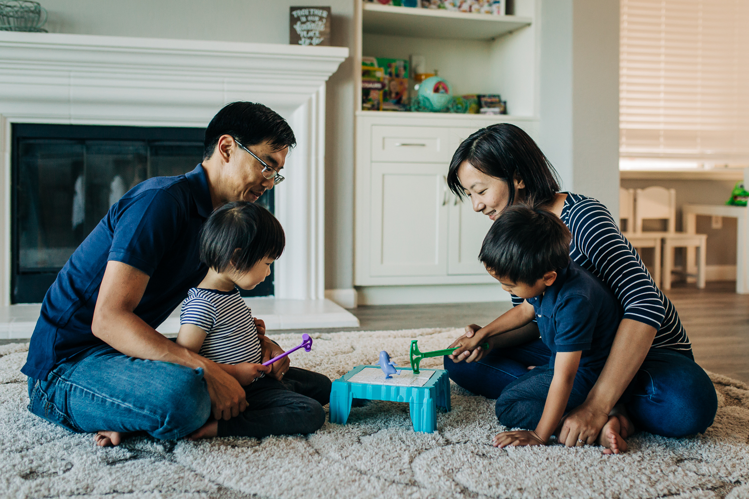 family of four sitting on the floor playing a board game together