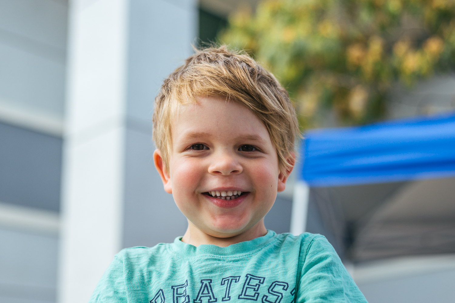 4 year old boy looking at camera outdoors and smiling