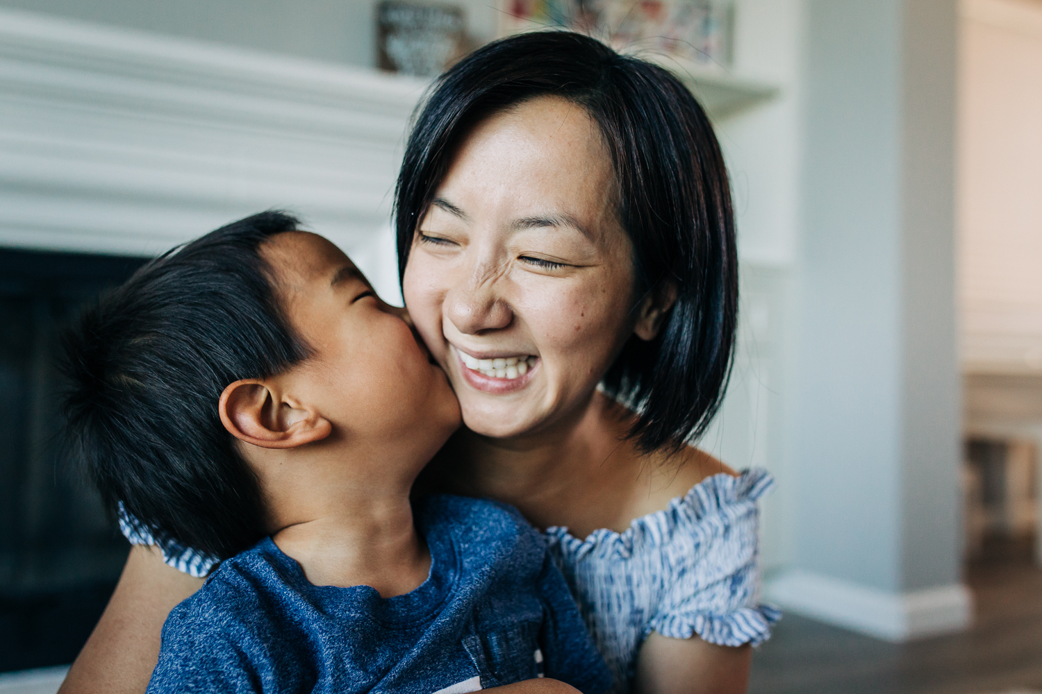 little boy kissing his mom as she smiles 