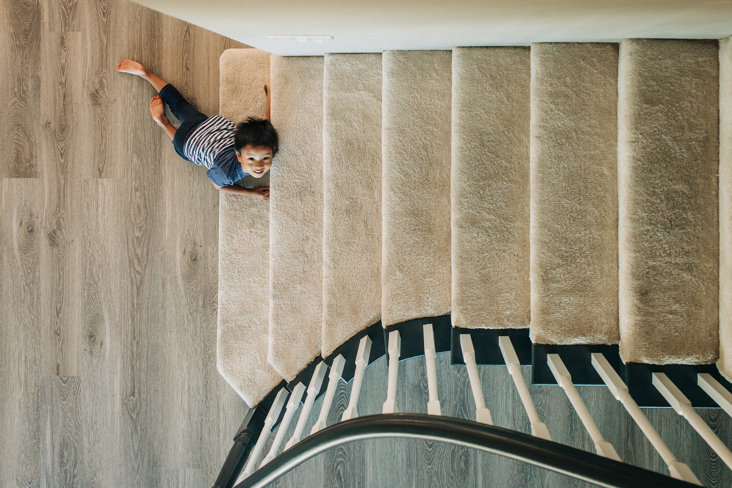 birds eye view of four year old boy as he lays at the bottom of the steps 