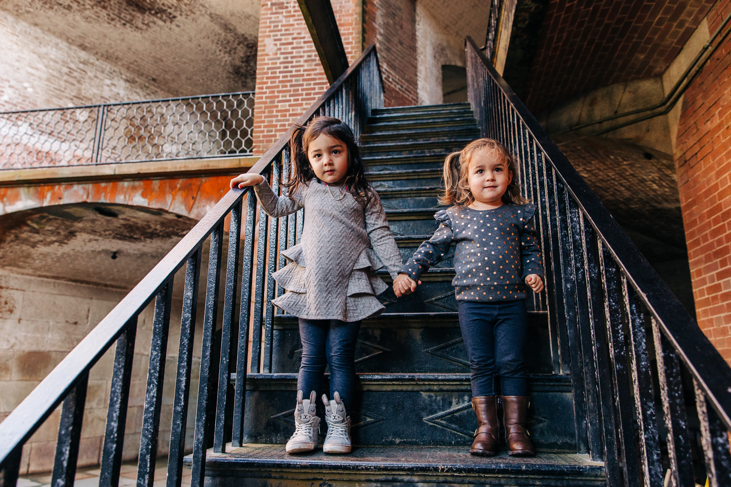 Two sisters standing on stairs and holding hands 