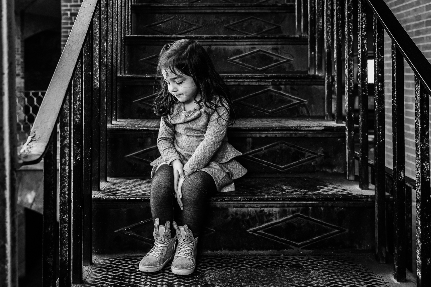 four year old girl sitting on stairs and looking down 