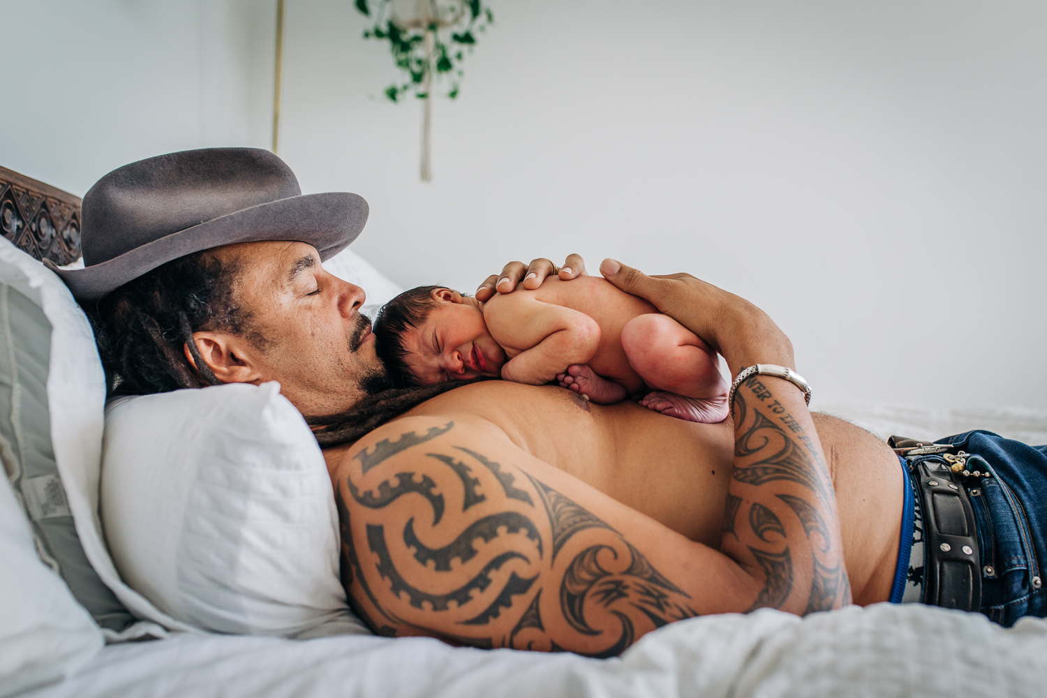 father with tattoos laying on the bed with his newborn soon sleeping on his chest | San Francisco Newborn Photography