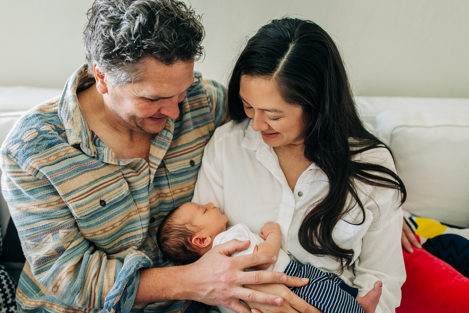 A new mother and father holding and looking down at their one week old baby boy 