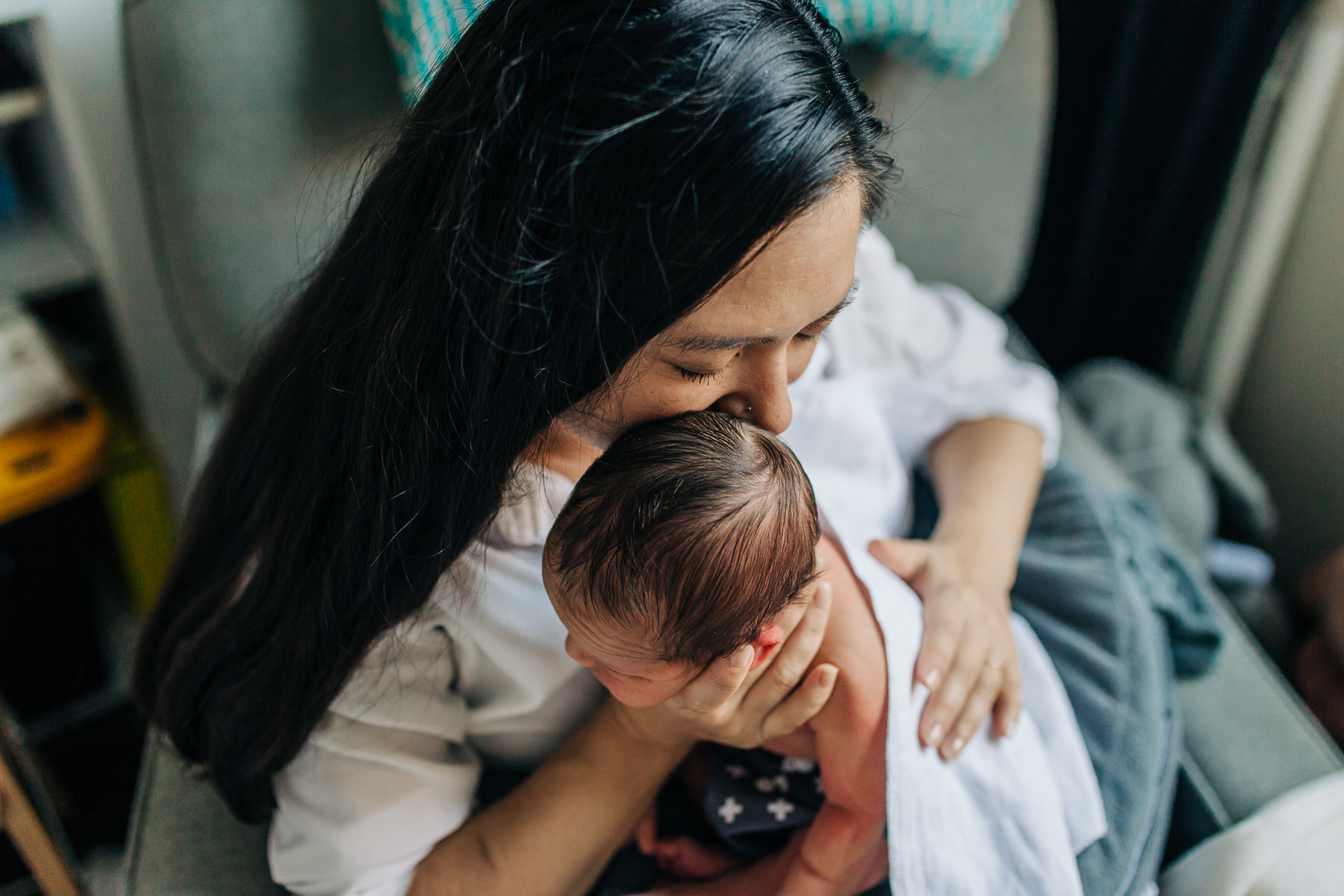 Mother holding and kissing her newborn boy as she burps him 