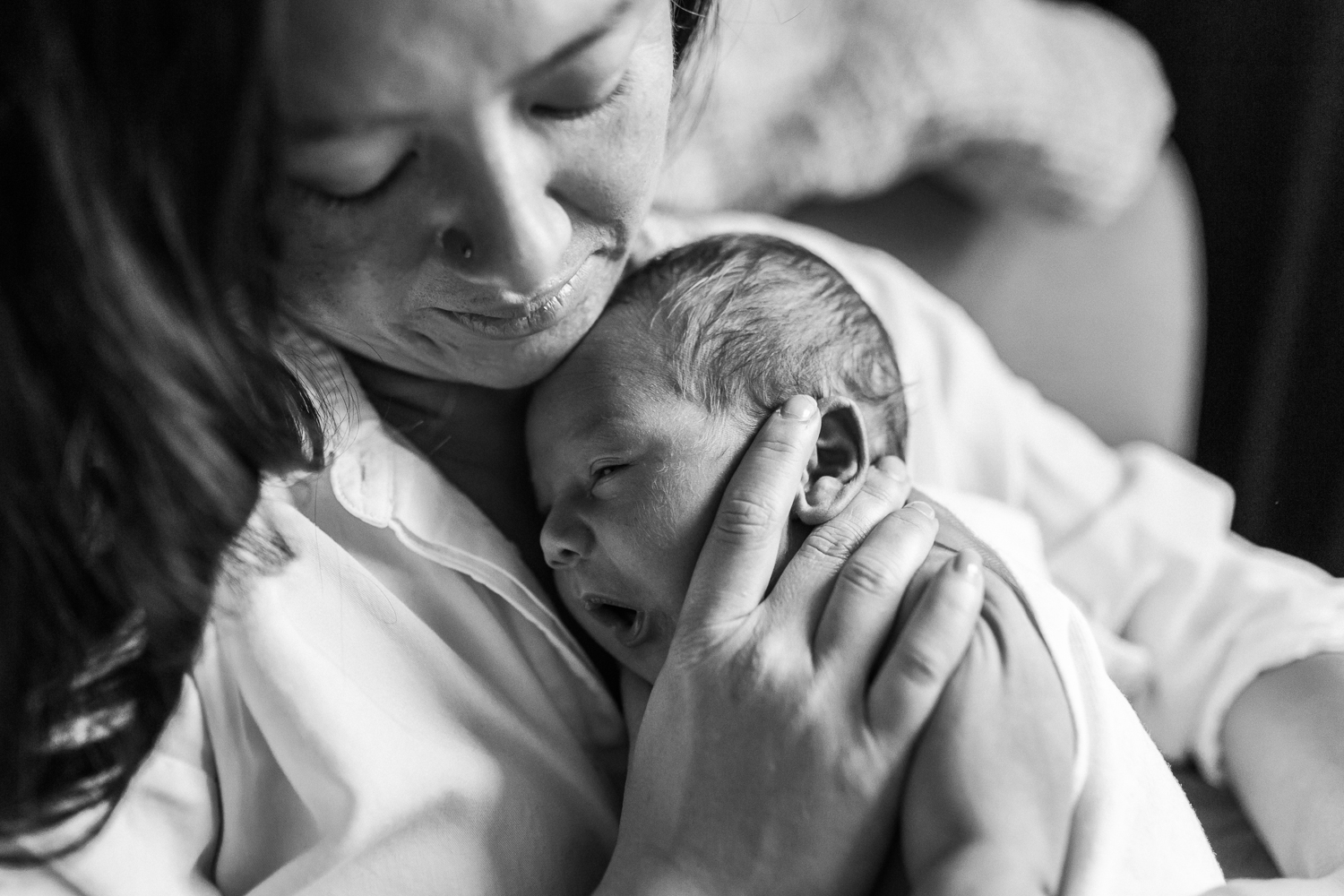 Mother supporting her baby boy's head and snuggling in close to him 