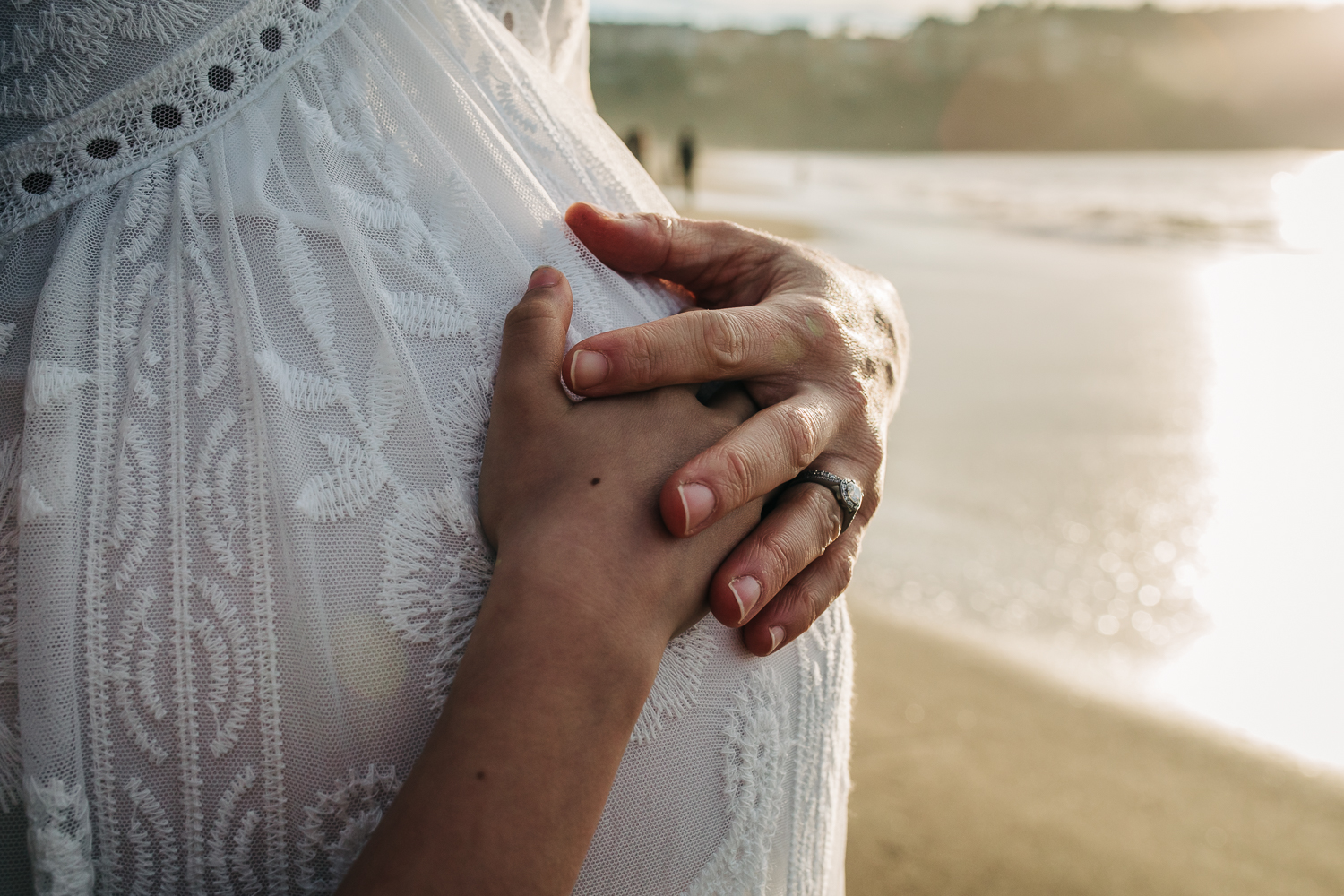 Mother and daughter holding hands on top of mother's baby bump 