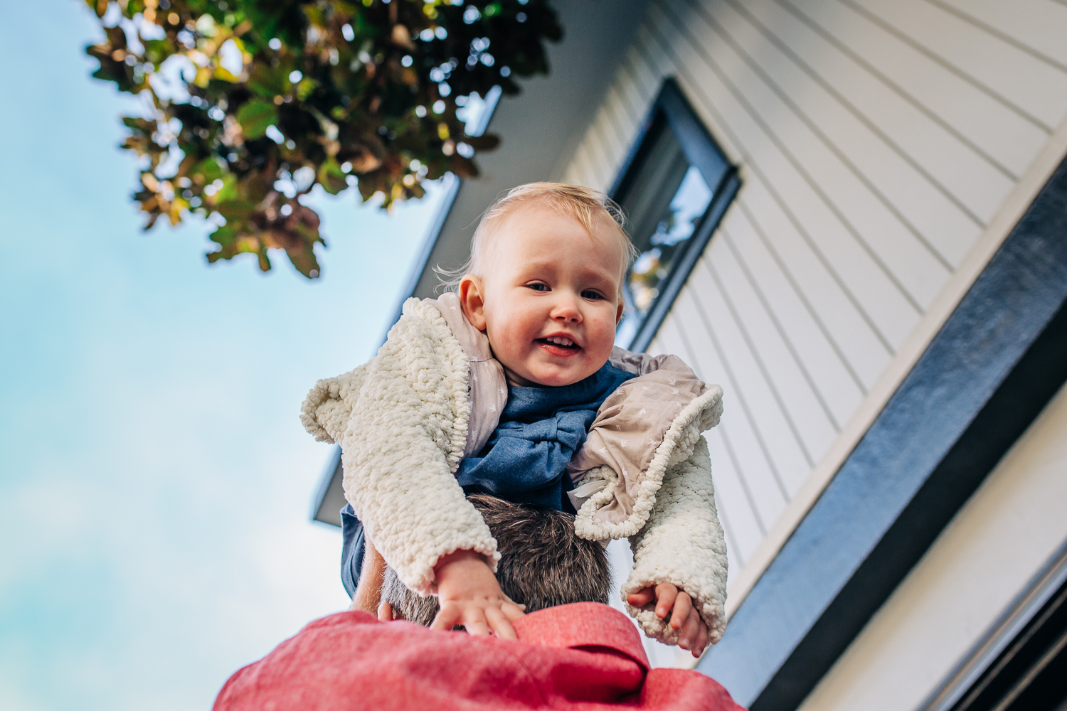 Little girl smiling as her dad lifts her over his head | Bay Area Baby Photographer