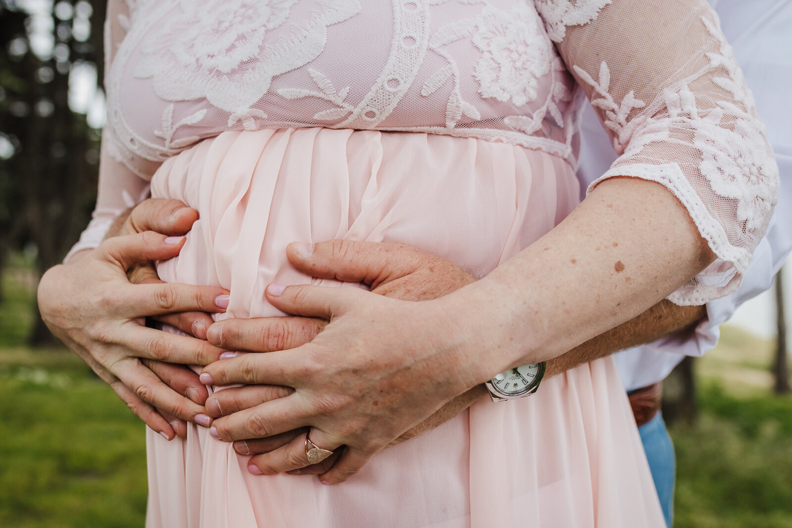 wife and partner's hands on pregnant belly 