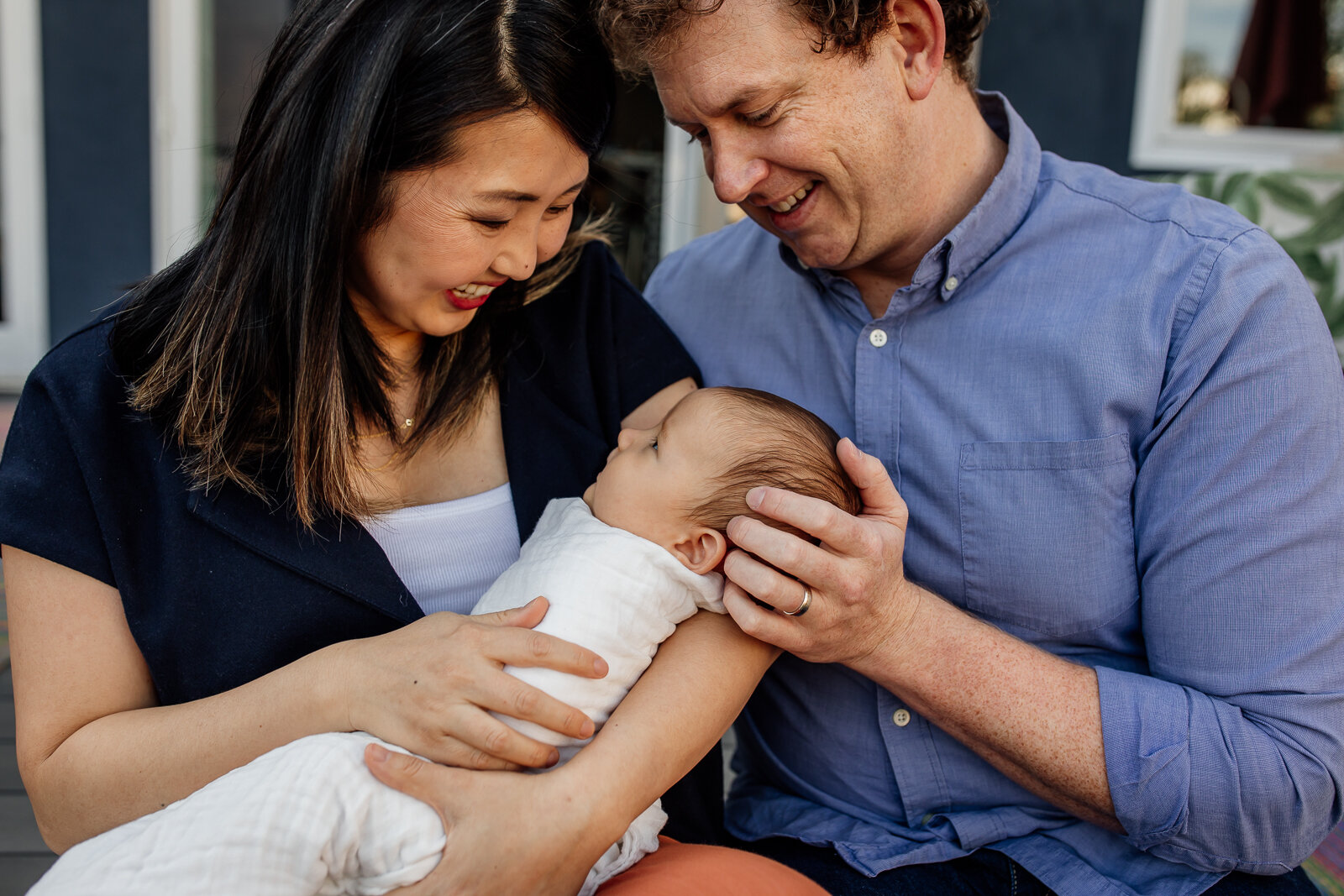 parents looking down and smiling while mom holds new baby 