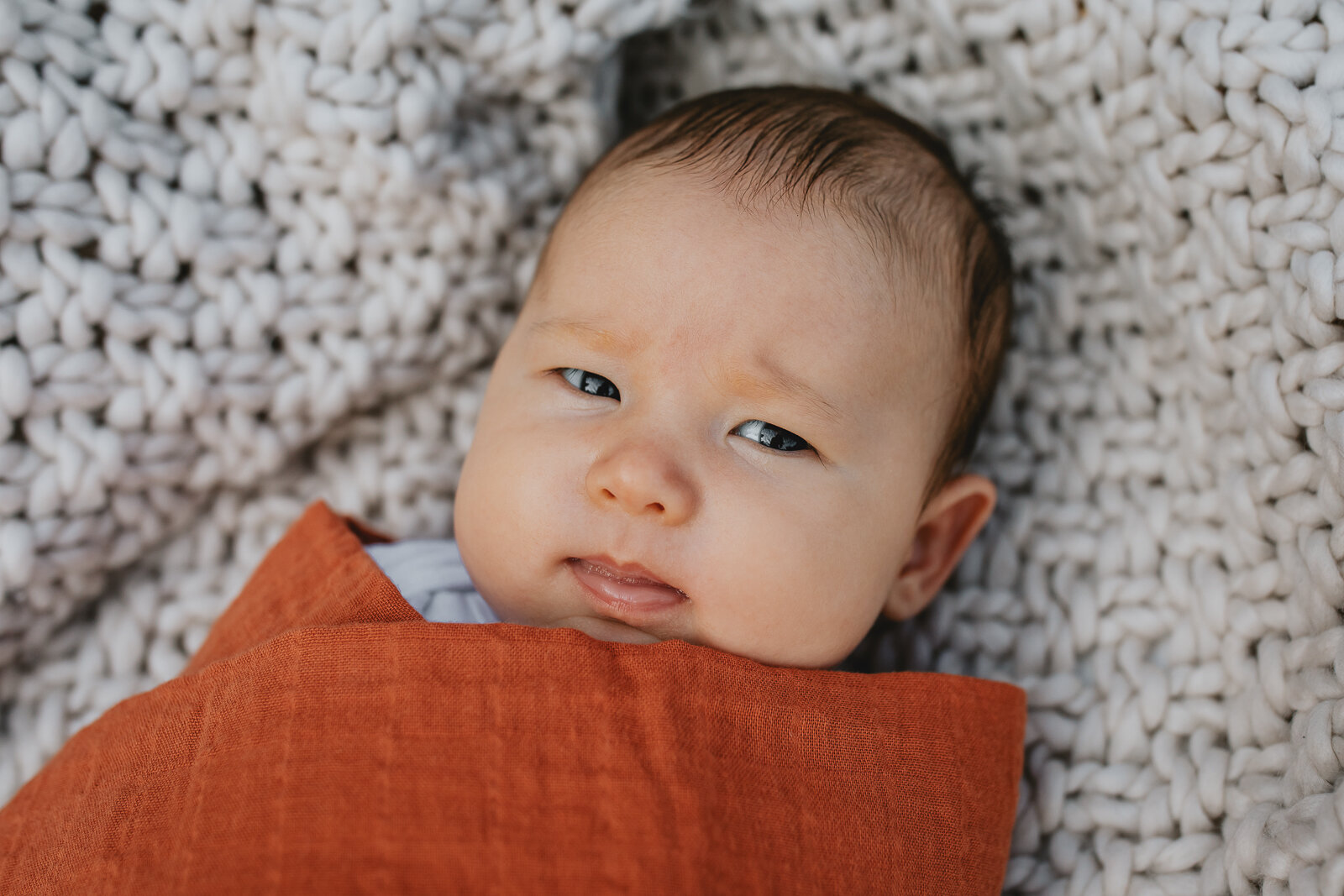 portrait of a baby boy swaddled and looking at camera 