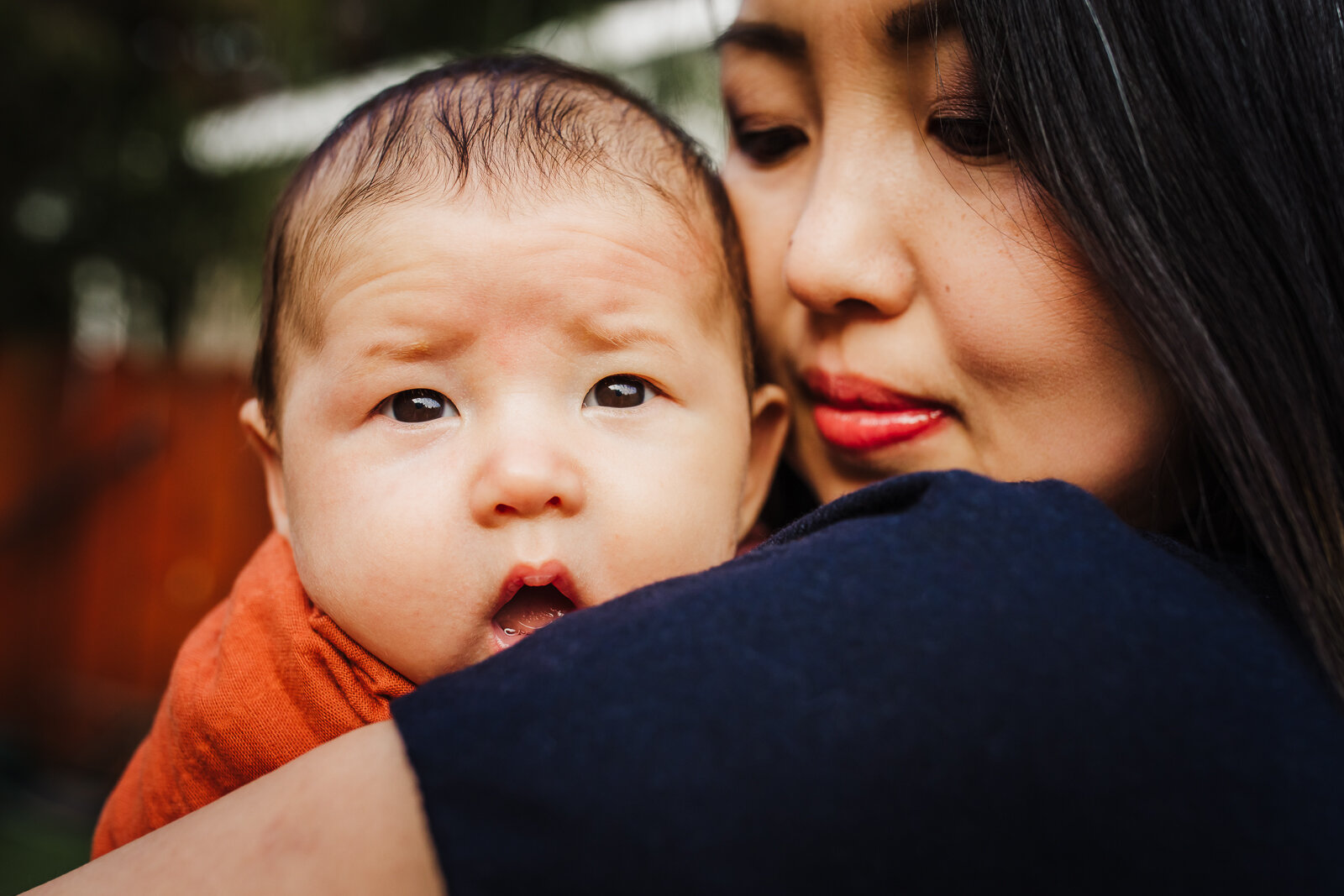 mom holding and snuggling baby as he looks at camera