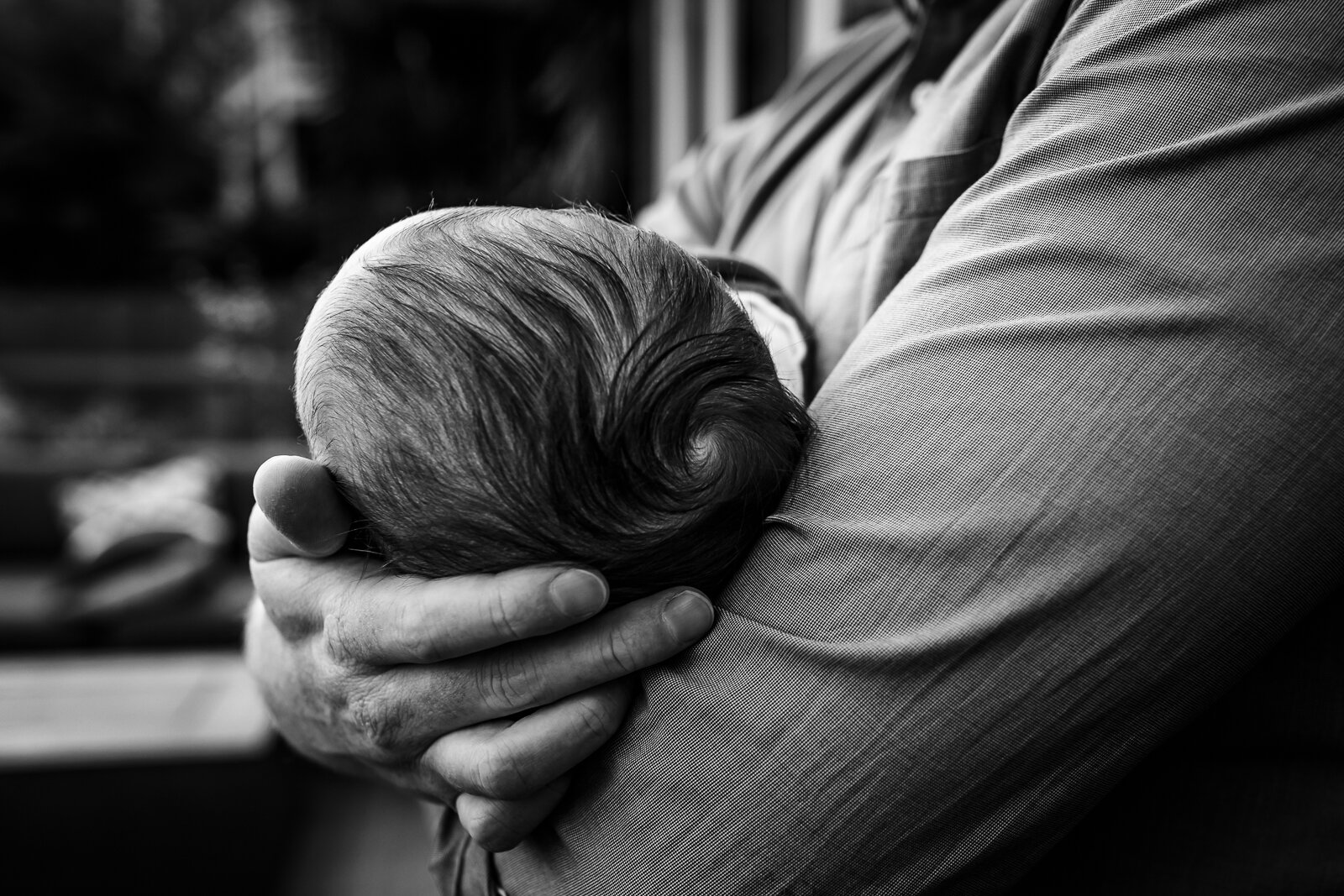 dad cradling baby boy in his arm and holding his head with the other hand 