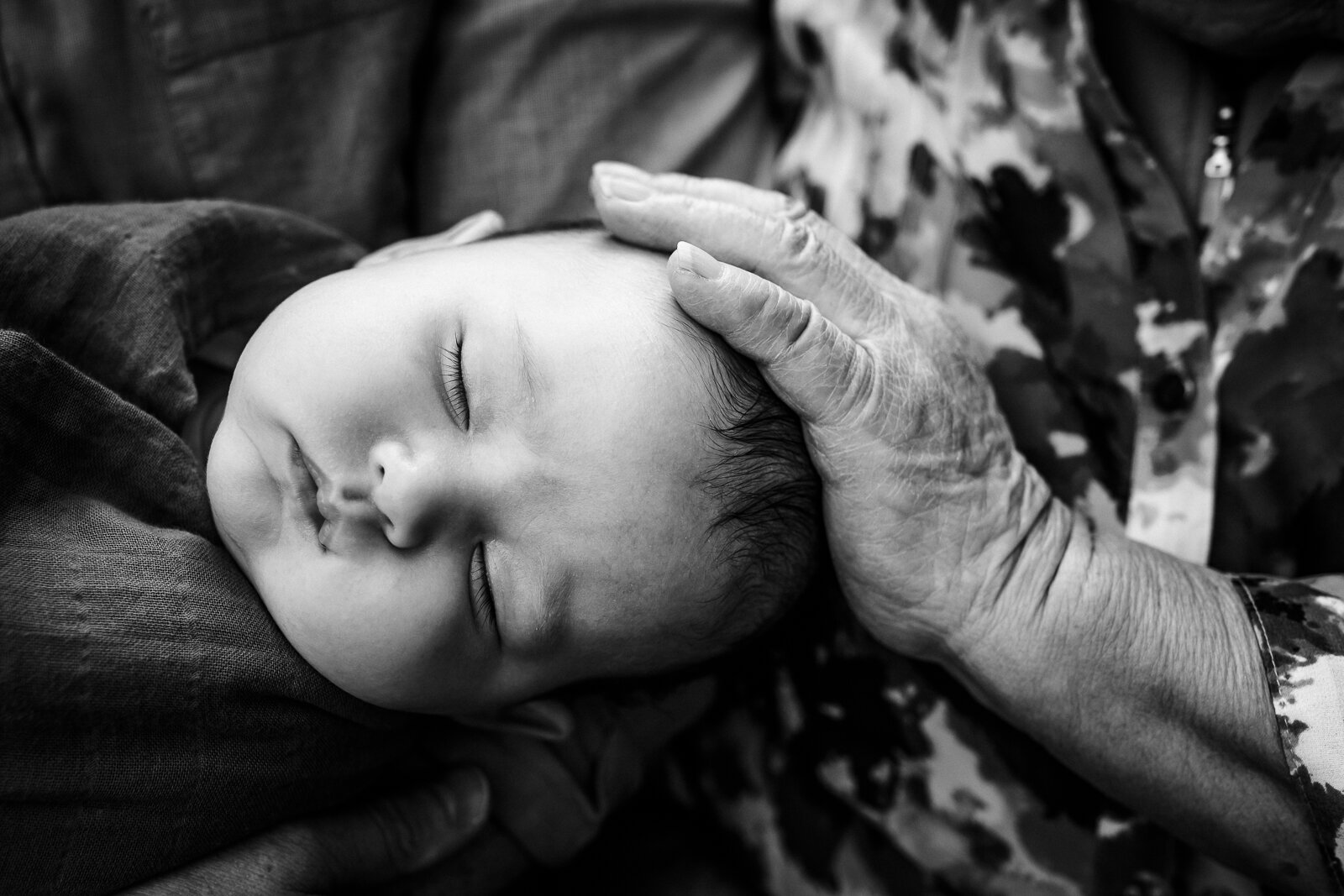 great grandmother touching baby grandson's head 