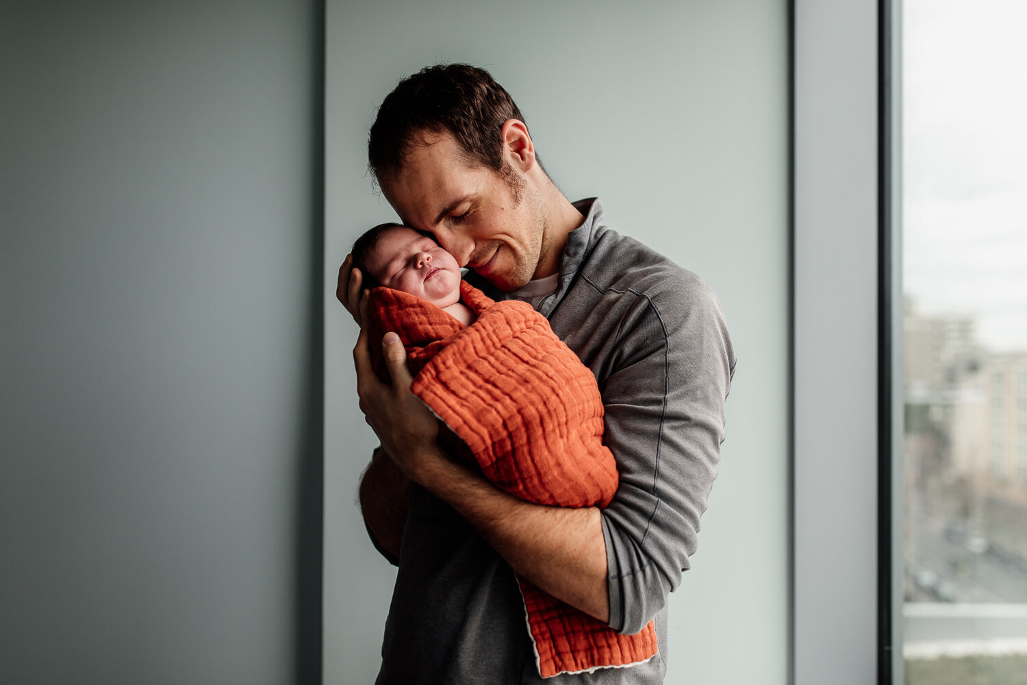 dad holding and snuggling swaddled newborn in hospital for Fresh 48