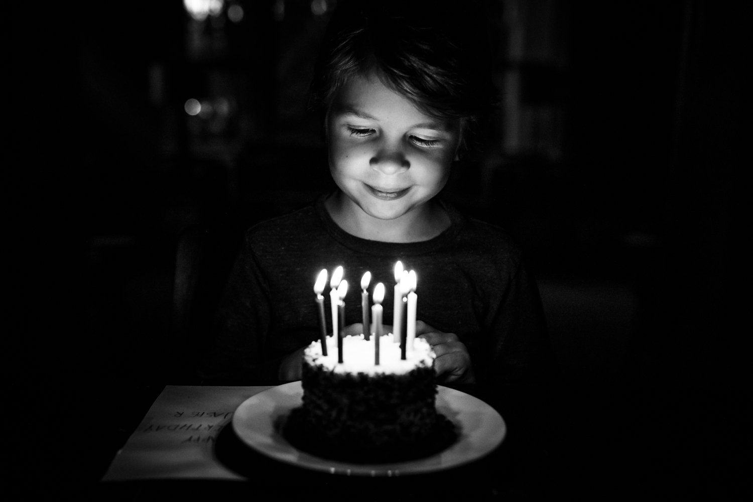 little boy smiling while looking at birthday cake