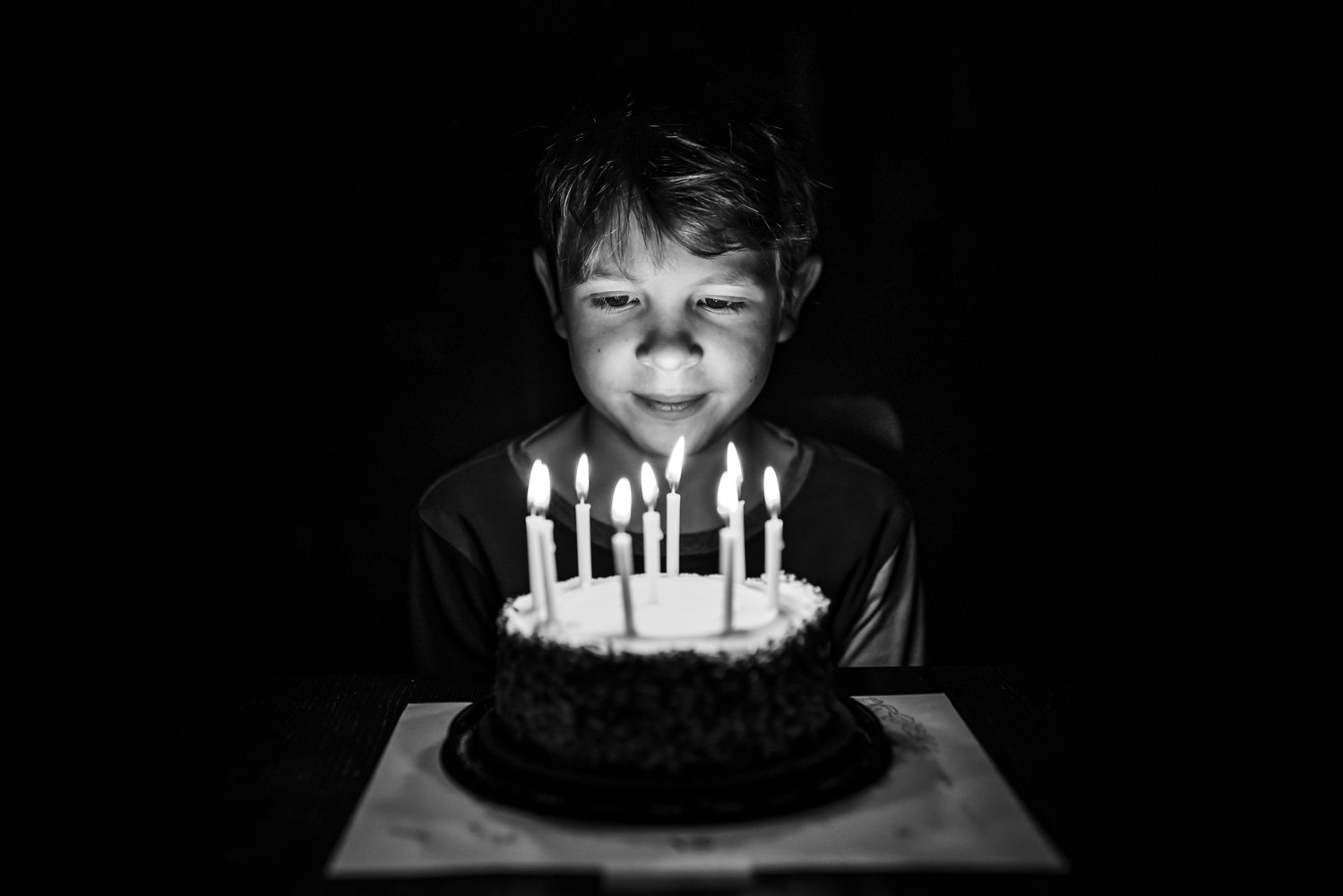 9 year old boy looking at candles on his birthday cake