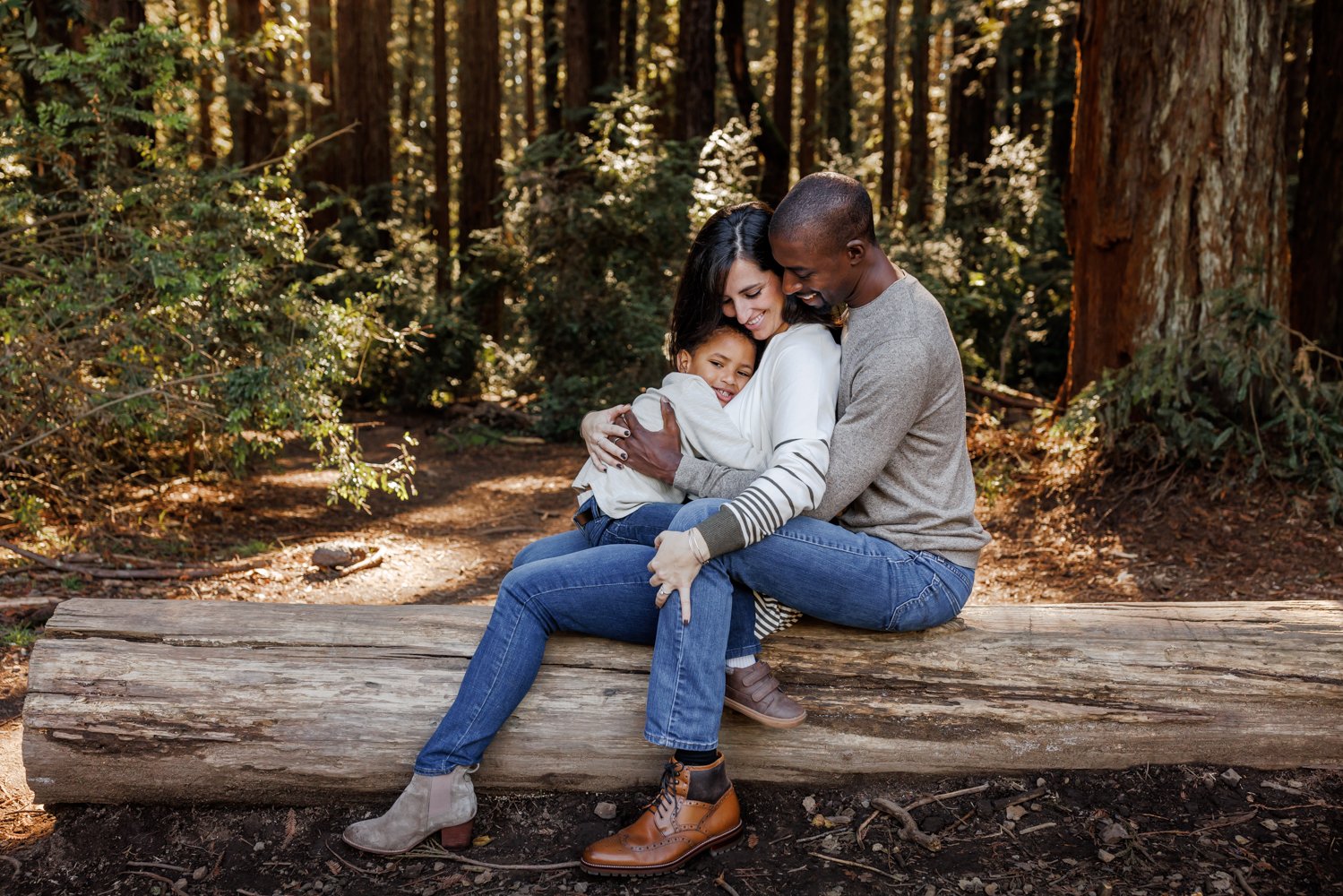 family of 3 snuggling in the woods