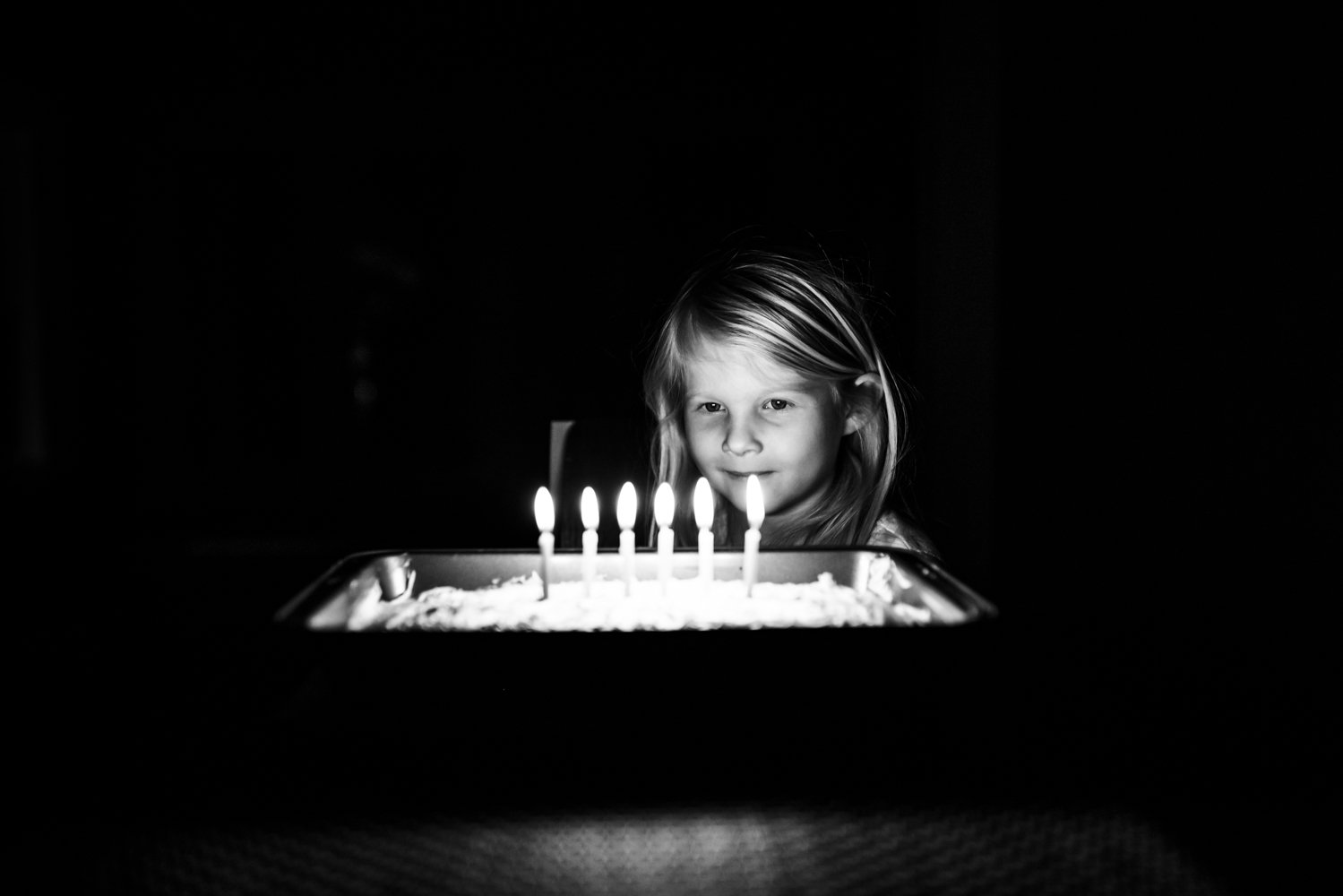 6 year old girl looking at birthday candles on her cake