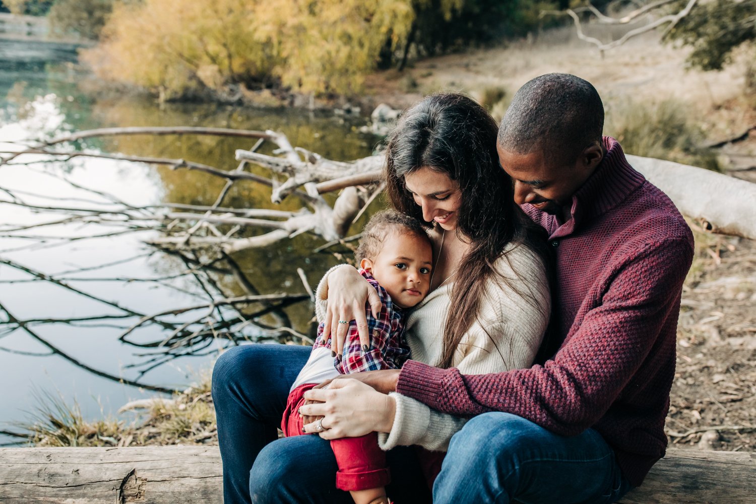 family of 3 sitting close together in nature