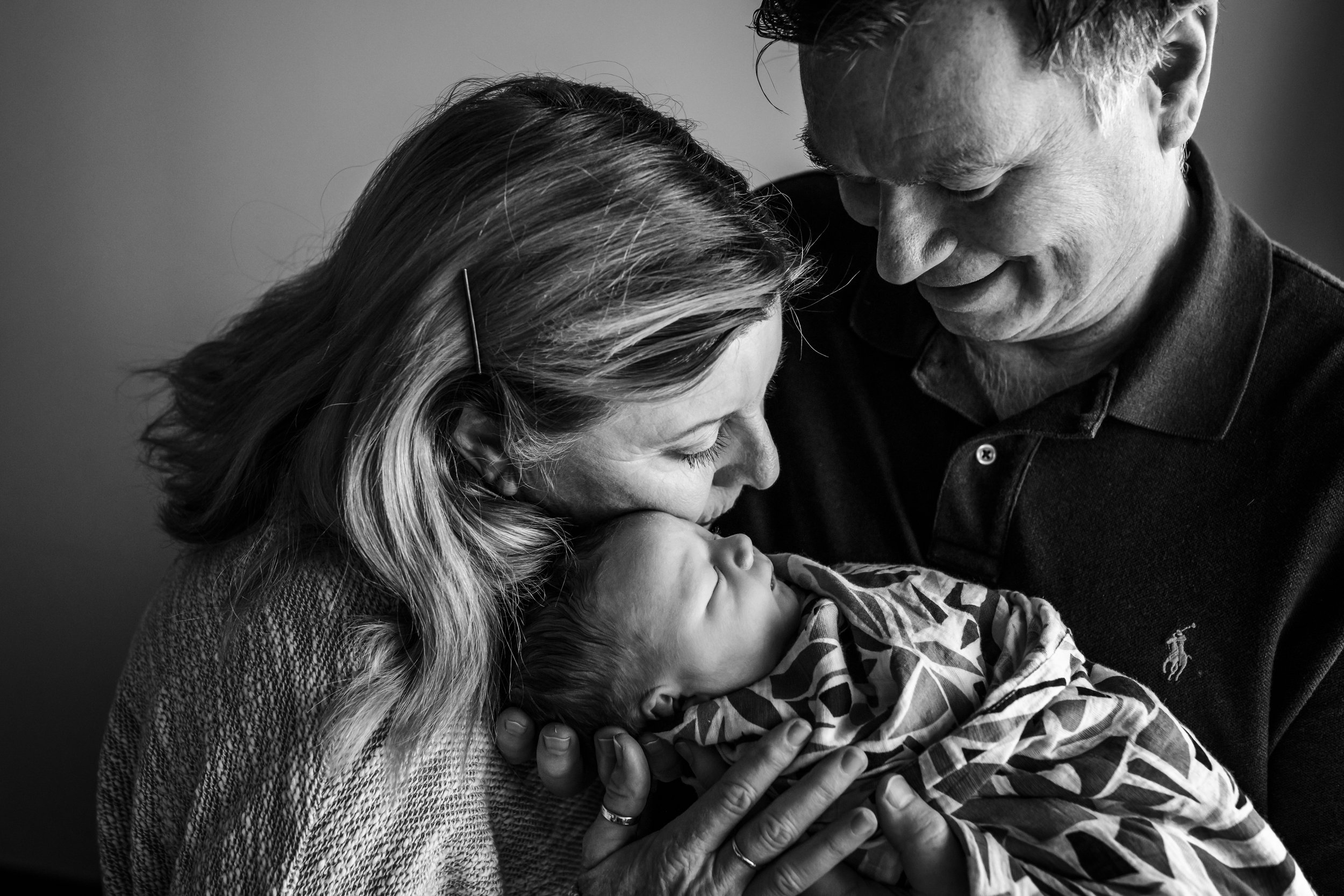 grandmother snuggling newborn grandson's face while he's held by his grandfather who is looking down and smiling at him during a San Francisco Fresh 48 session.jpg