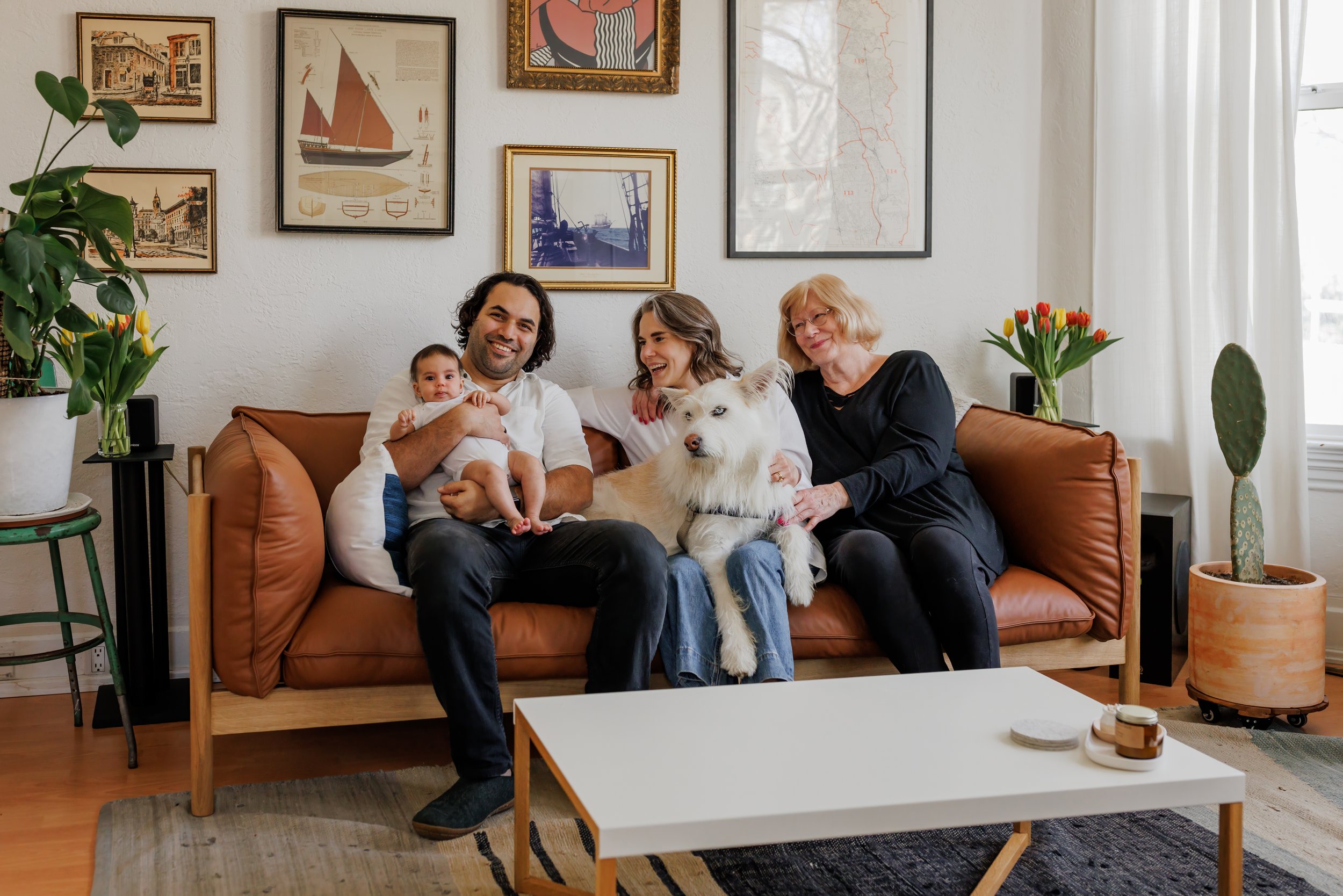 parents sitting on the couch with their baby, dog, and grandma during East Bay in-home session.jpg