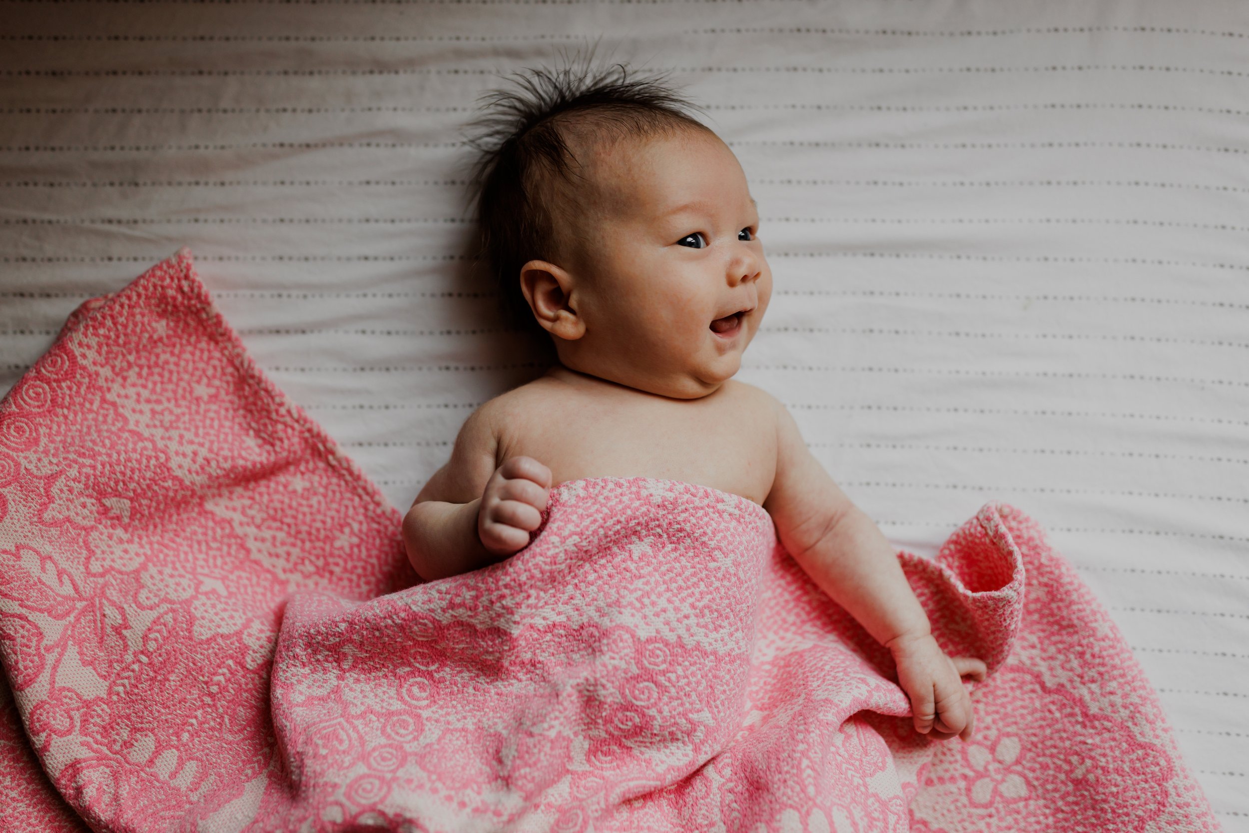 birds eye view portrait of baby girl laying on bed draped in pink blanket