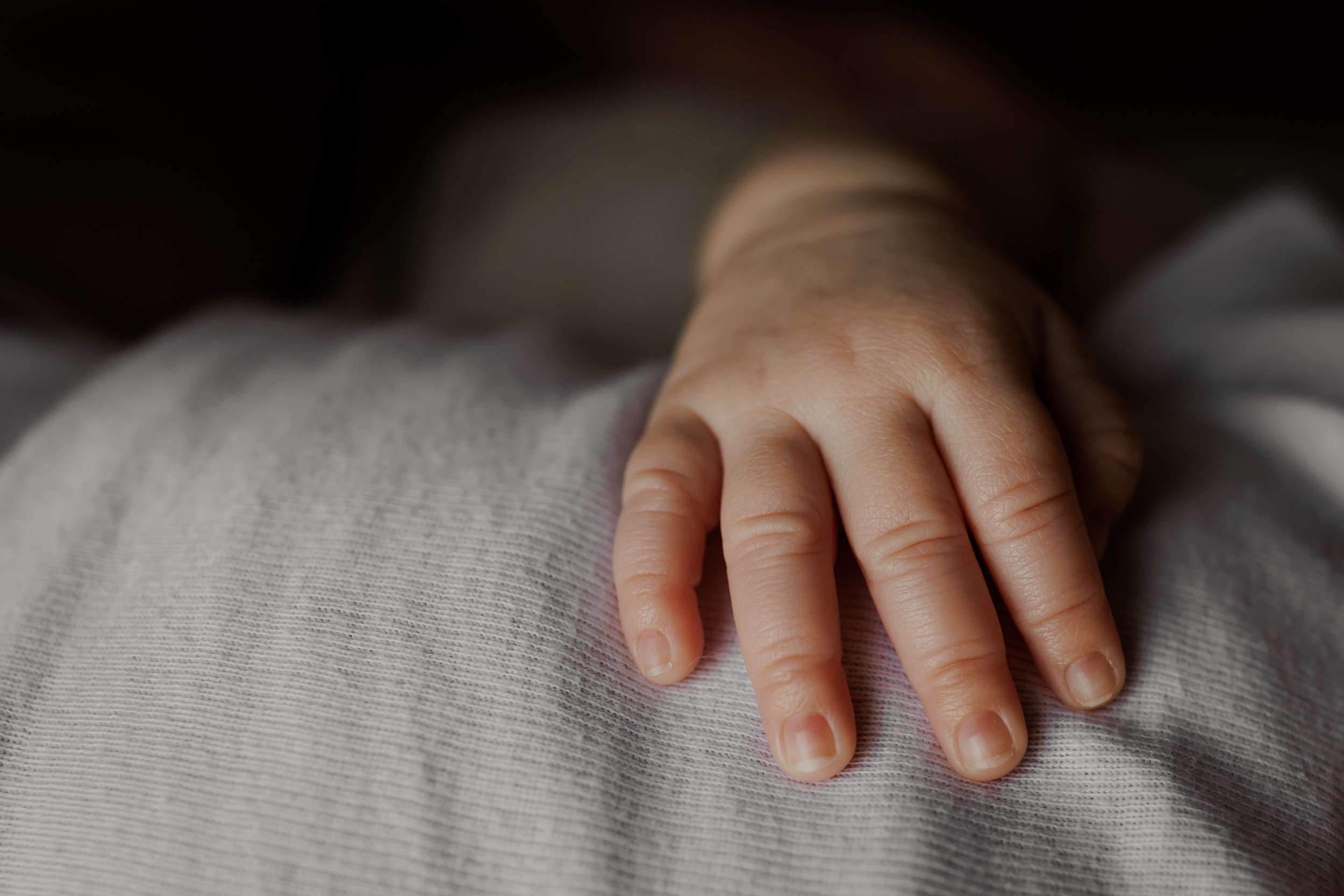 close up of newborn's hand resting on baby's chest