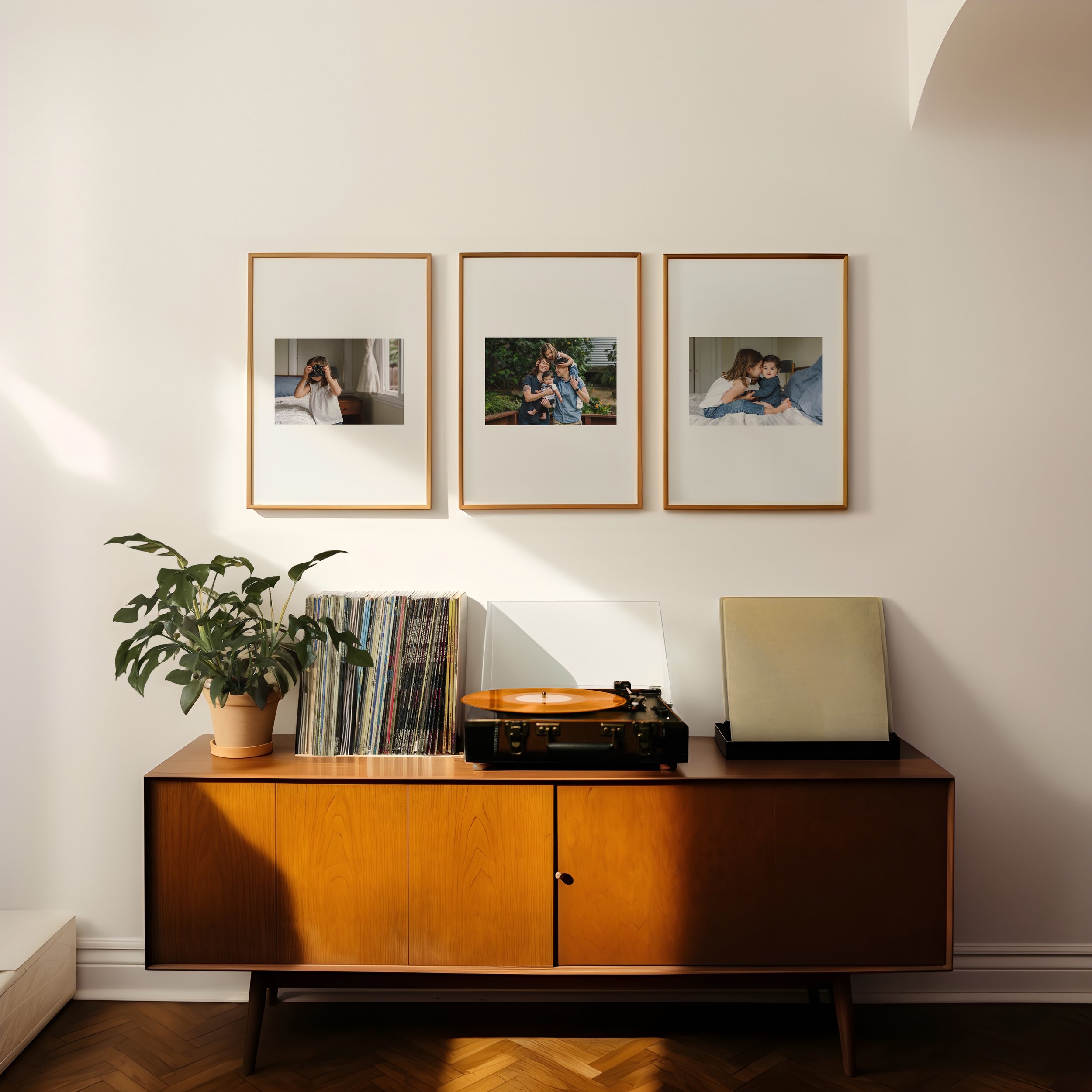 3-family-prints-hanging-on-wall-behind-shelf-with-plant-and-record-player