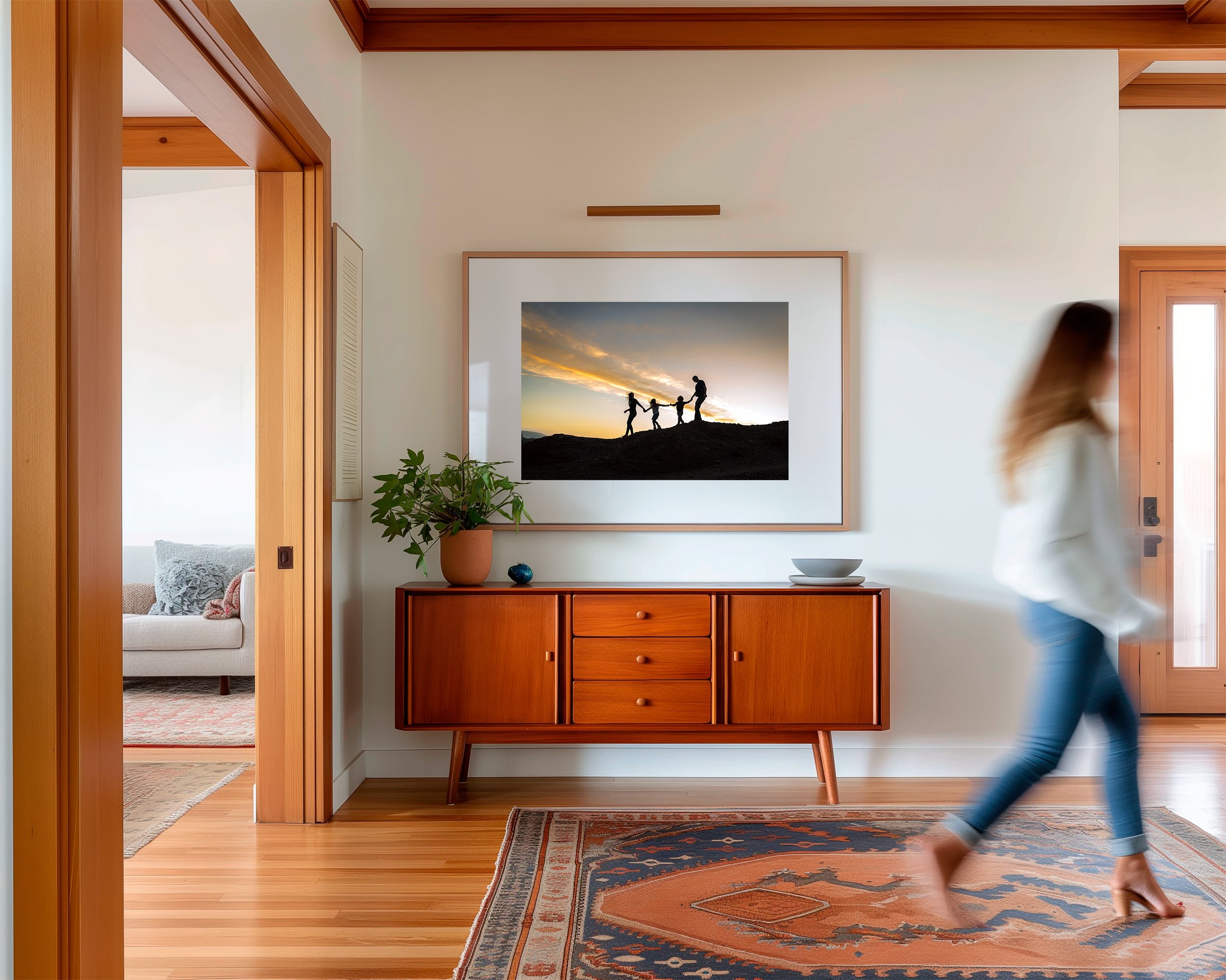 silhouette of a family of four hanging on the wall in a hallway while a woman walks past