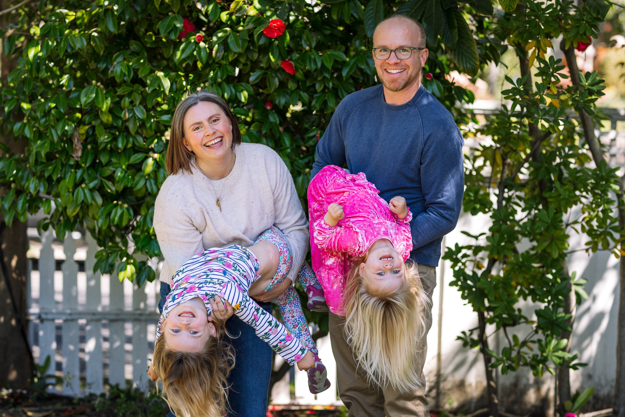 family portrait with mom and dad holding preschool and toddler daugthers upside down