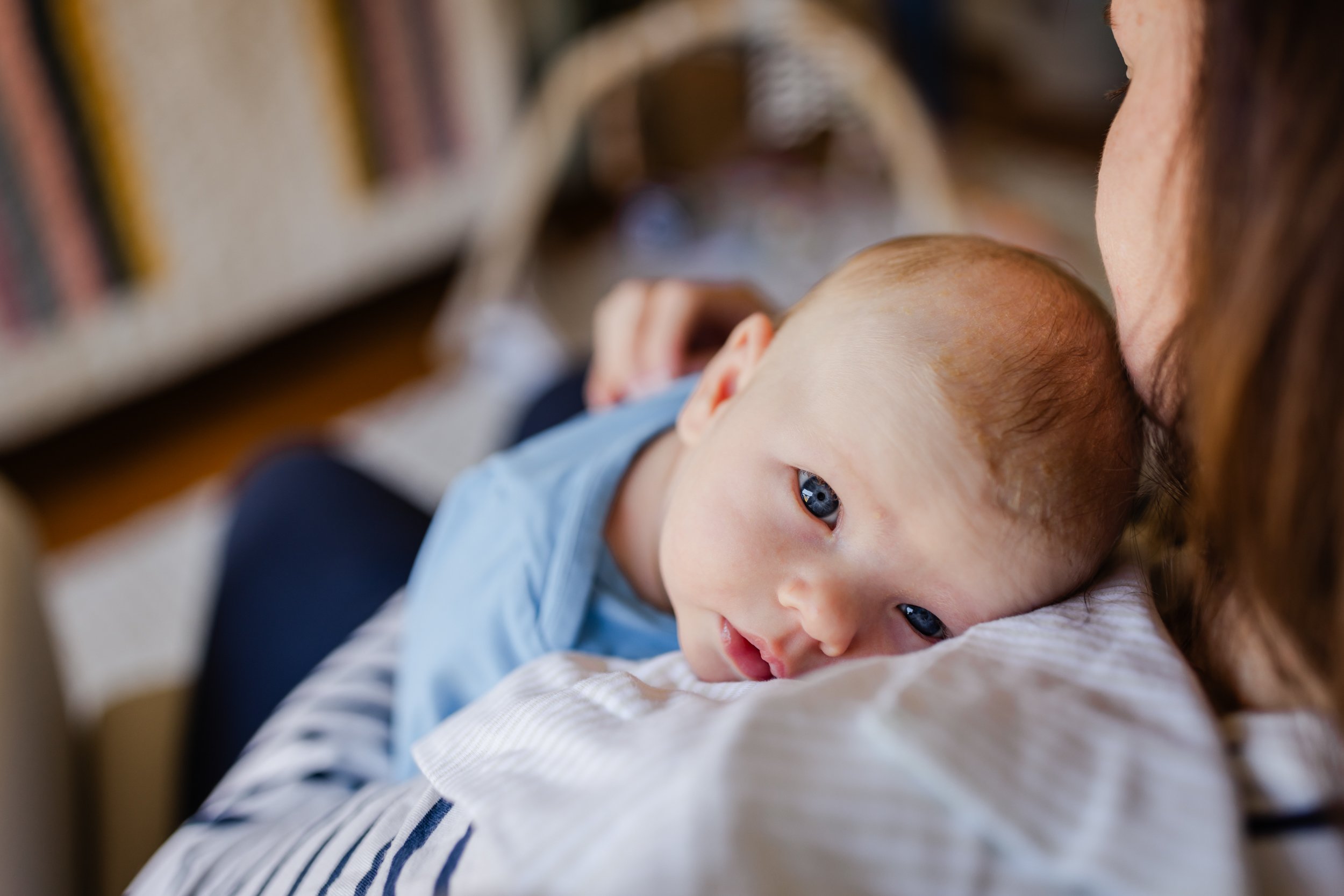 baby laying on mom's shoulder with eyes open and looking up towards the camera