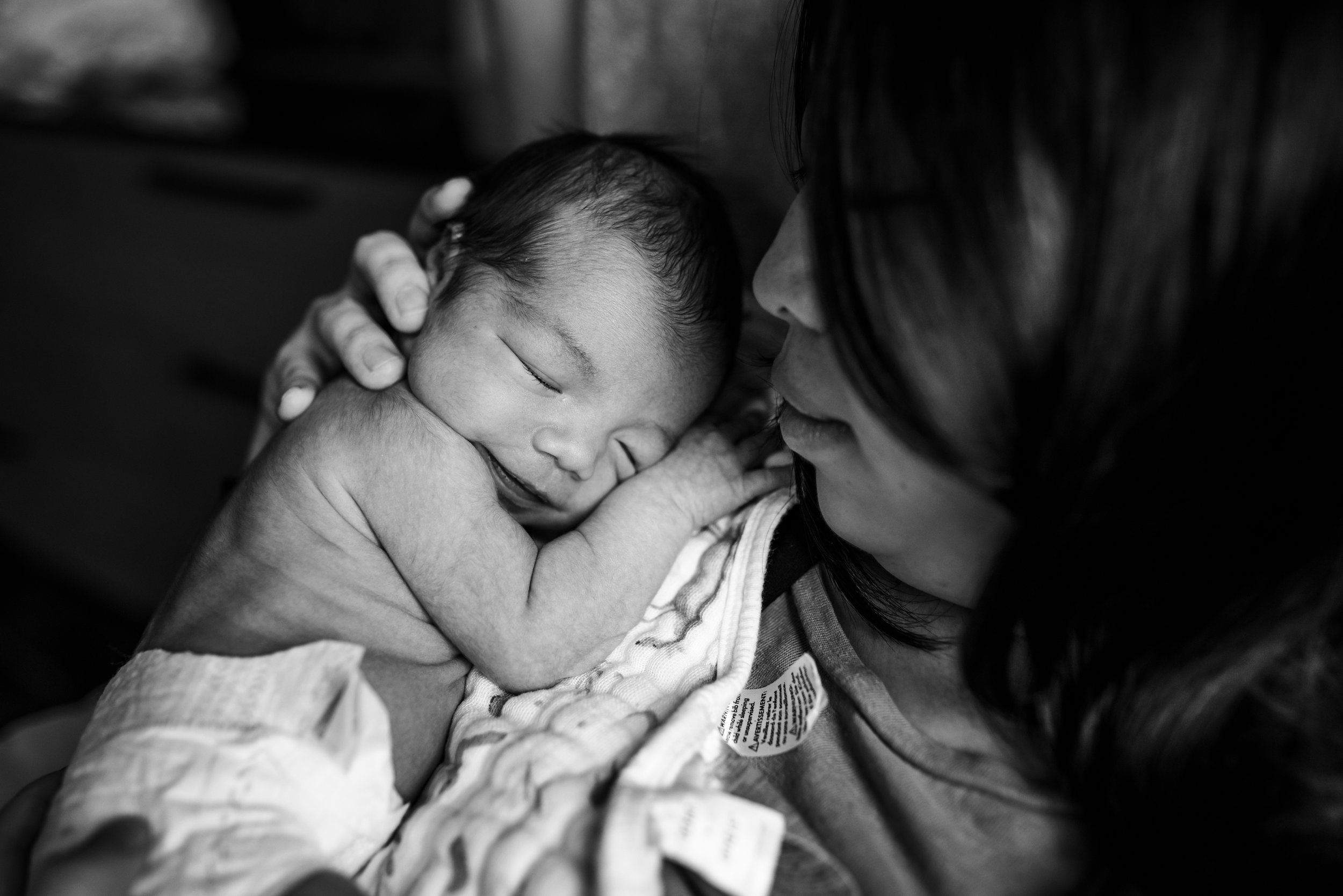 black and white photo of baby in a diaper sleeping on mom's shoulder