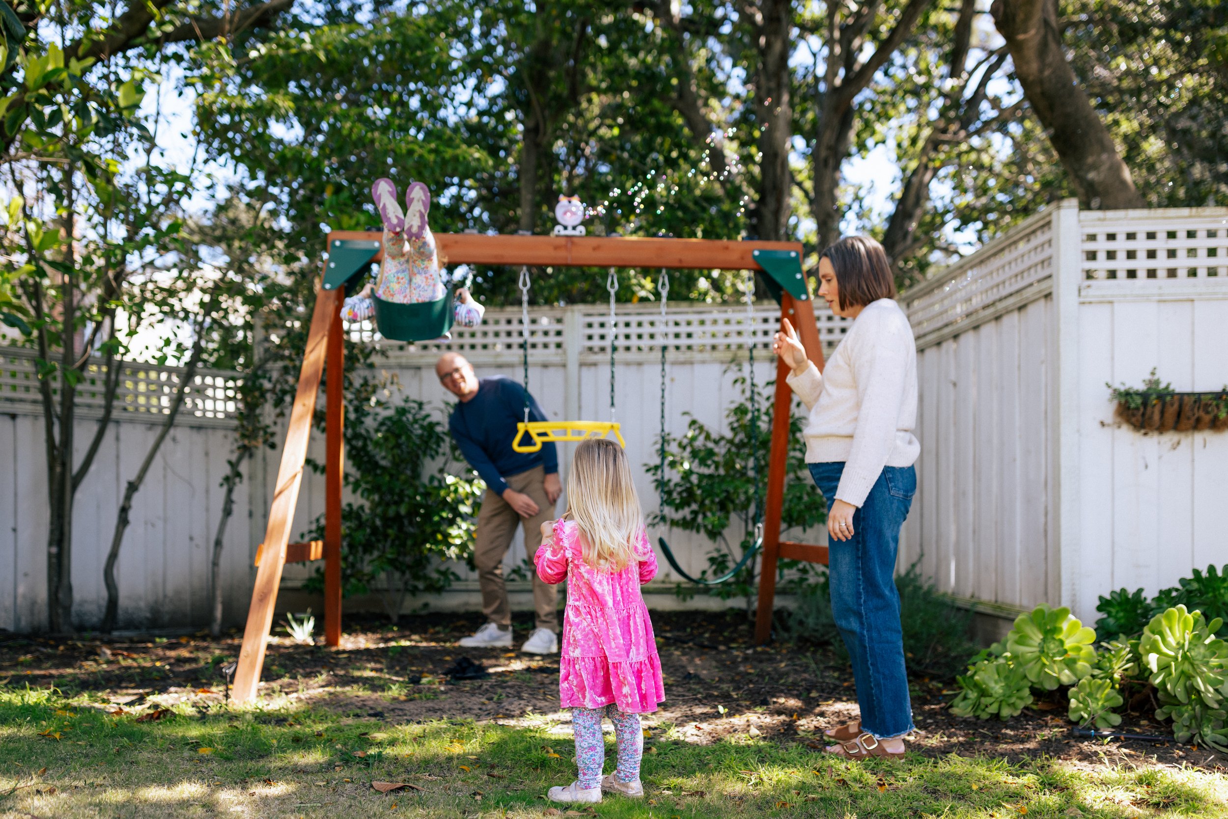 family of four all together around play structure in the backyard