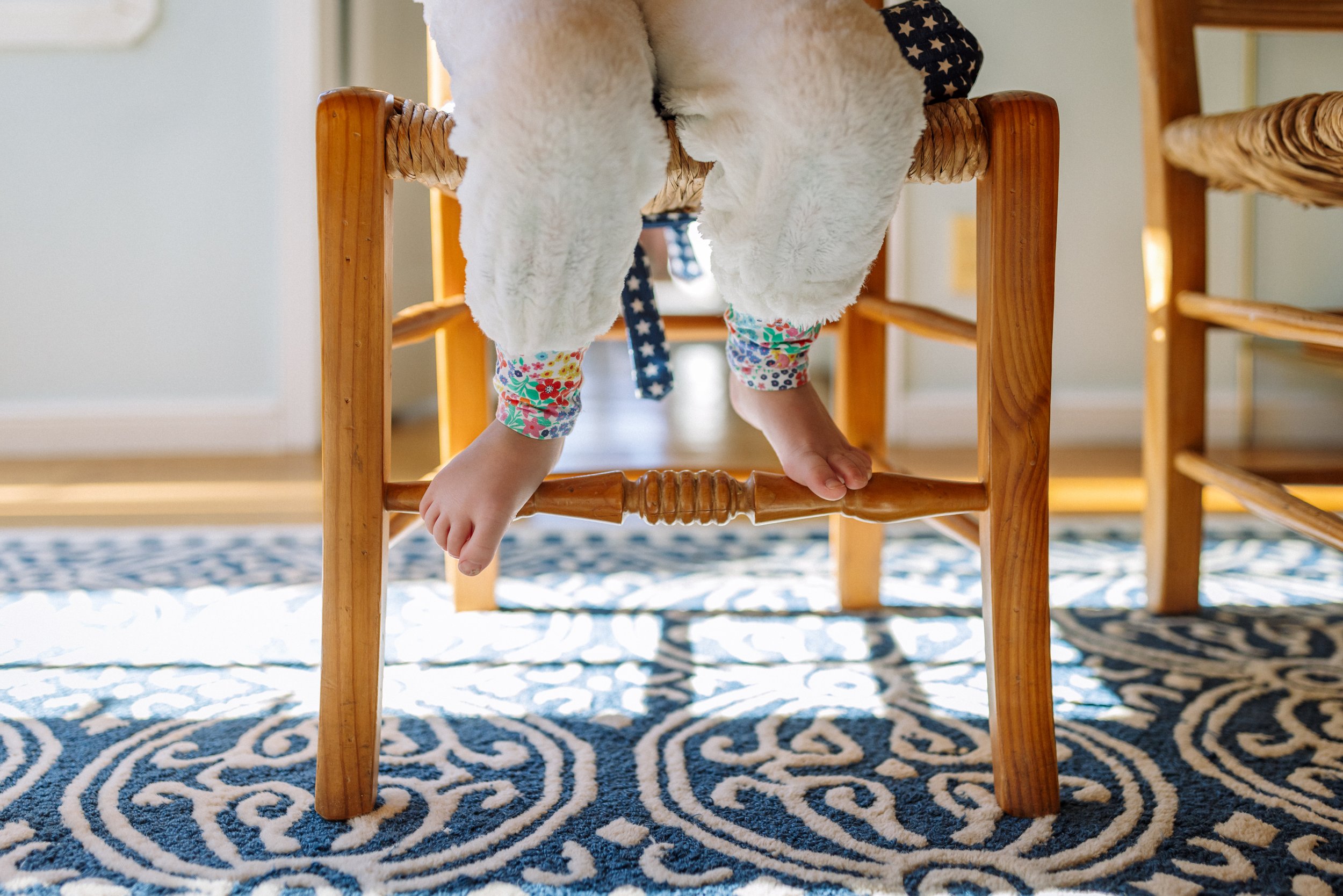 feet of preschool girl wearing unicorn costume while sitting at table for snack