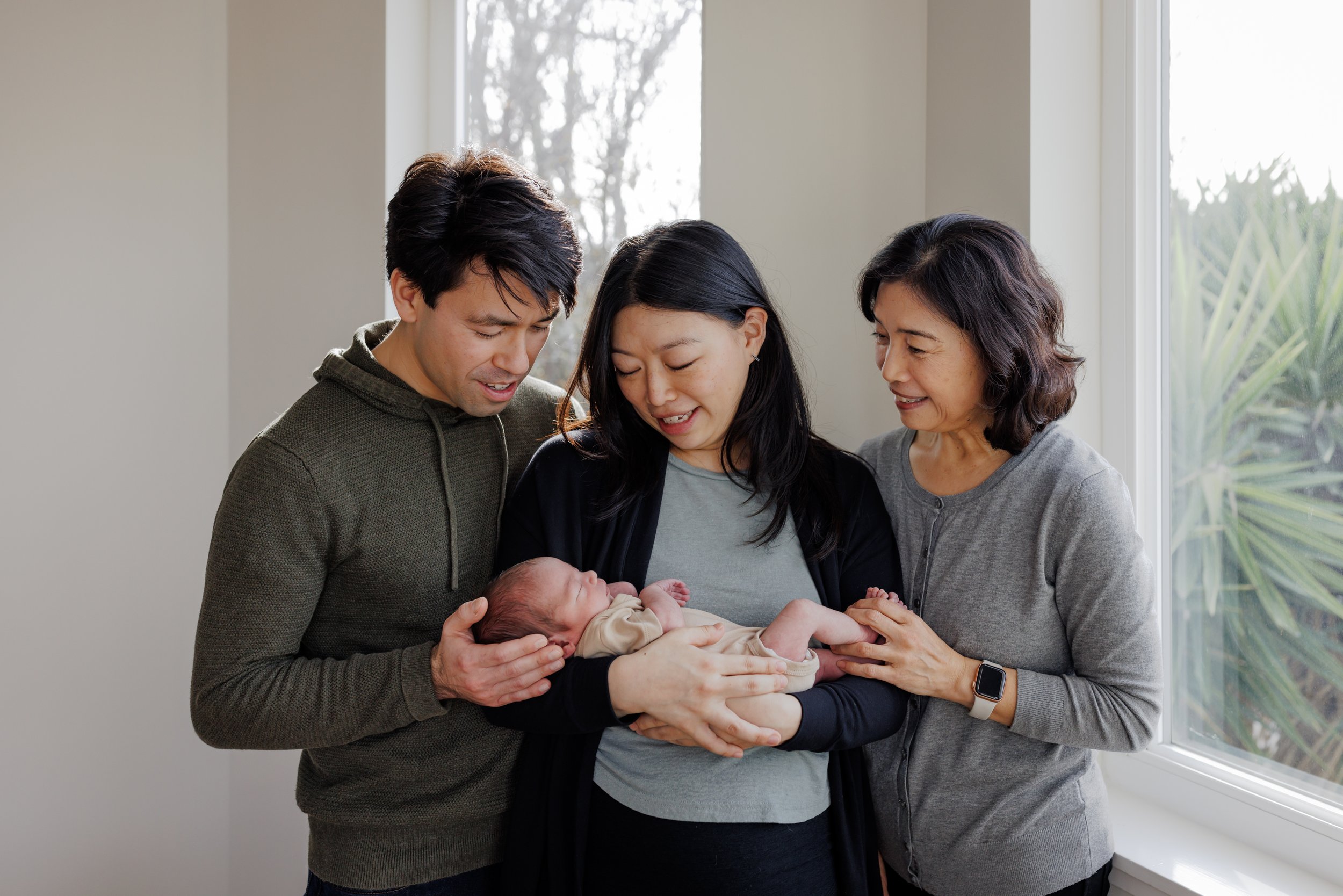 portrait of mom holding newborn baby with grandma on one side of her and dad on the other