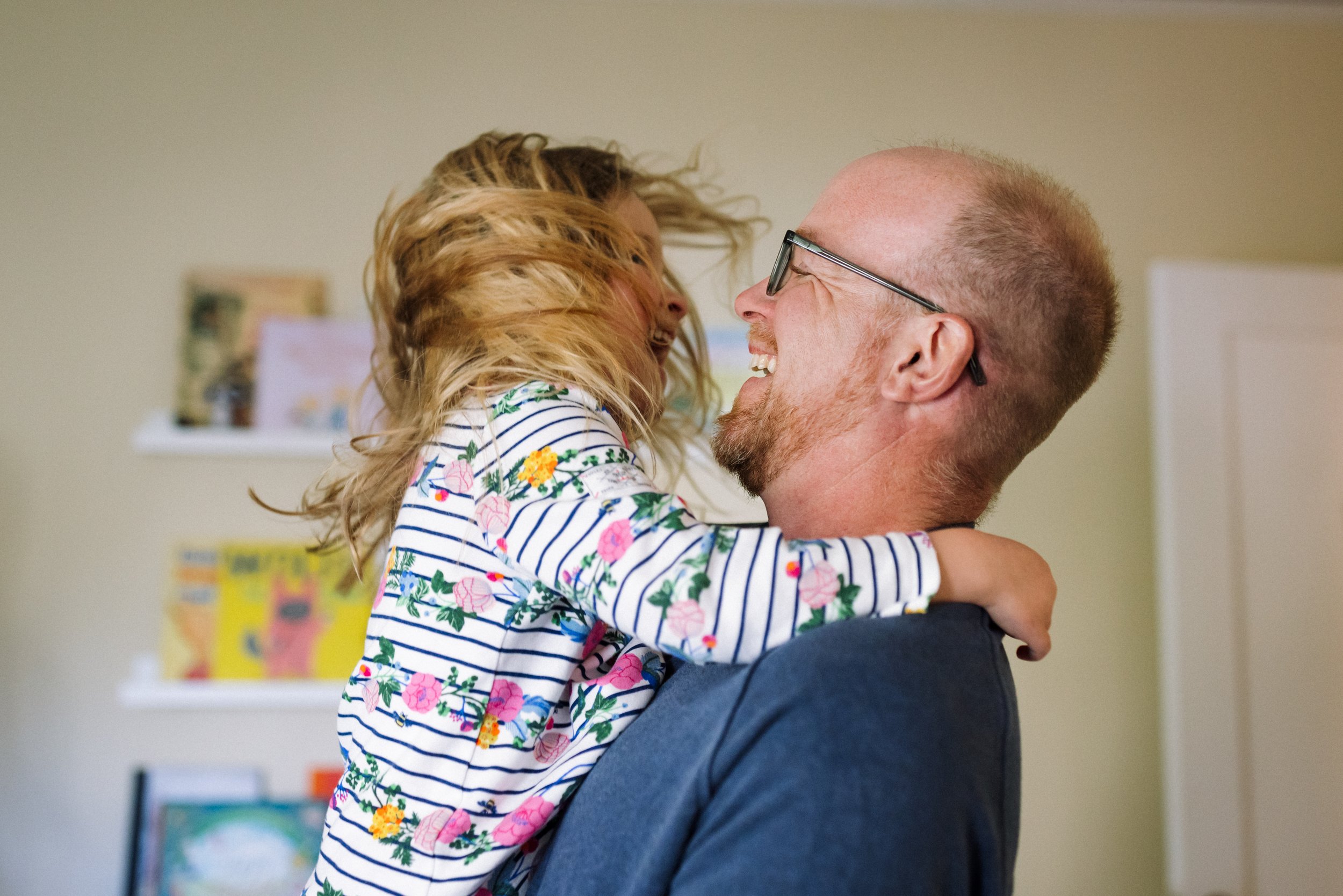 Dad and preschool-aged daughter dancing together and looking at each other and laughing