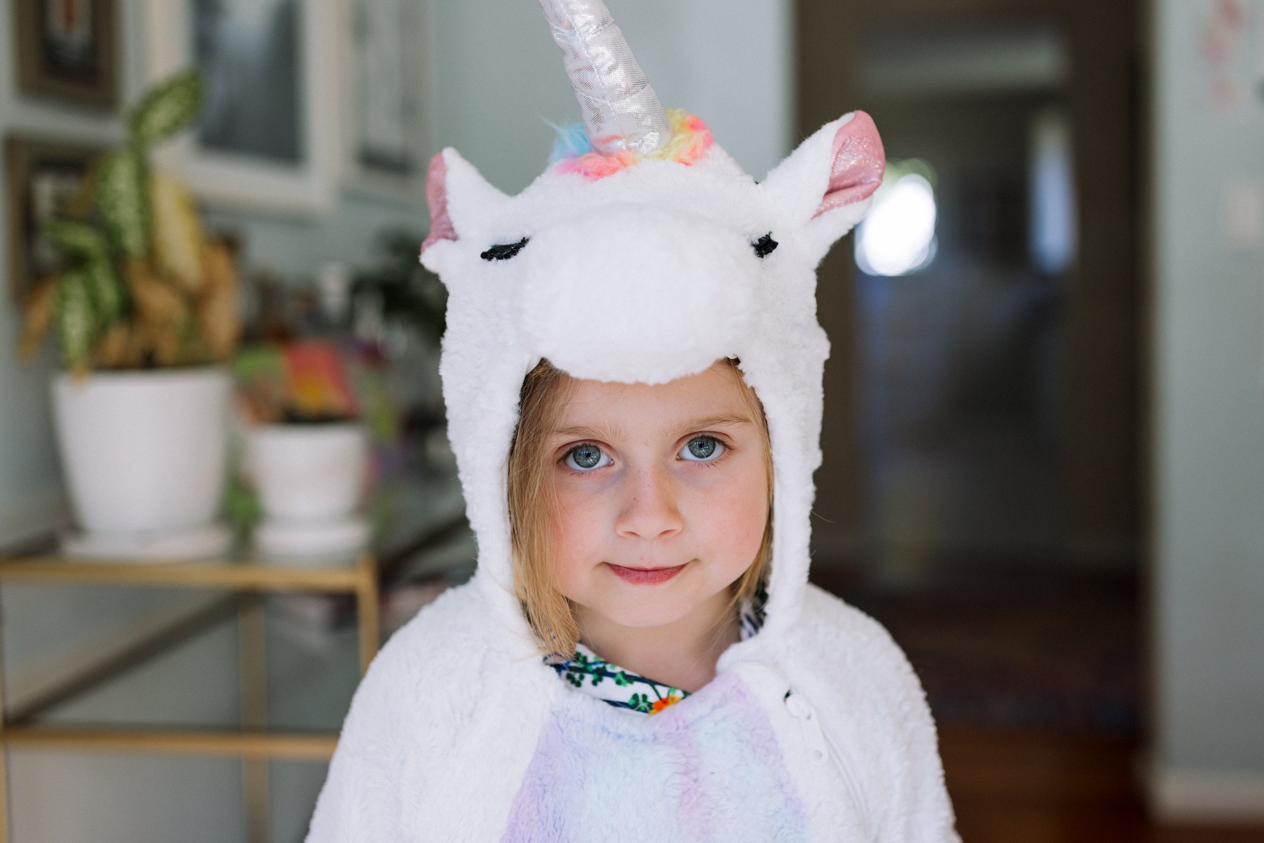 portrait of preschool-aged girl in unicorn costume looking at the camera