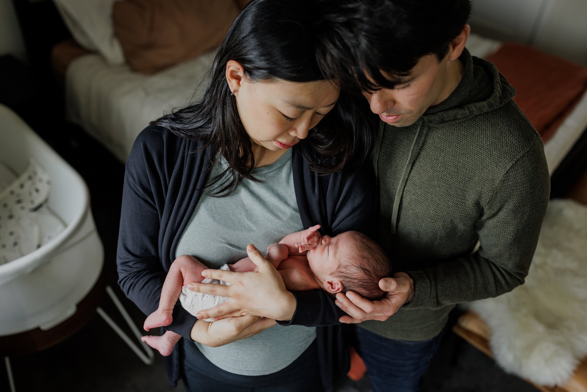 birdseye view of mom holding newborn baby while dad gently touches his head